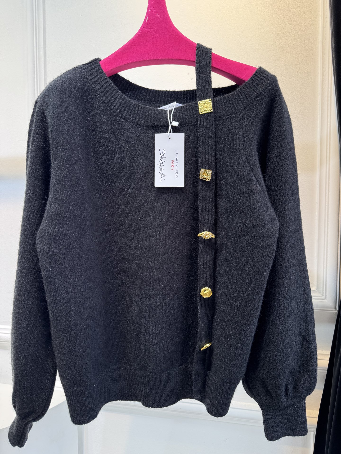 schiaparelli 侧纽扣设计的米白色针织衫短款版型，侧边采用斜排金属纽扣设计，兼具装饰性与实用性