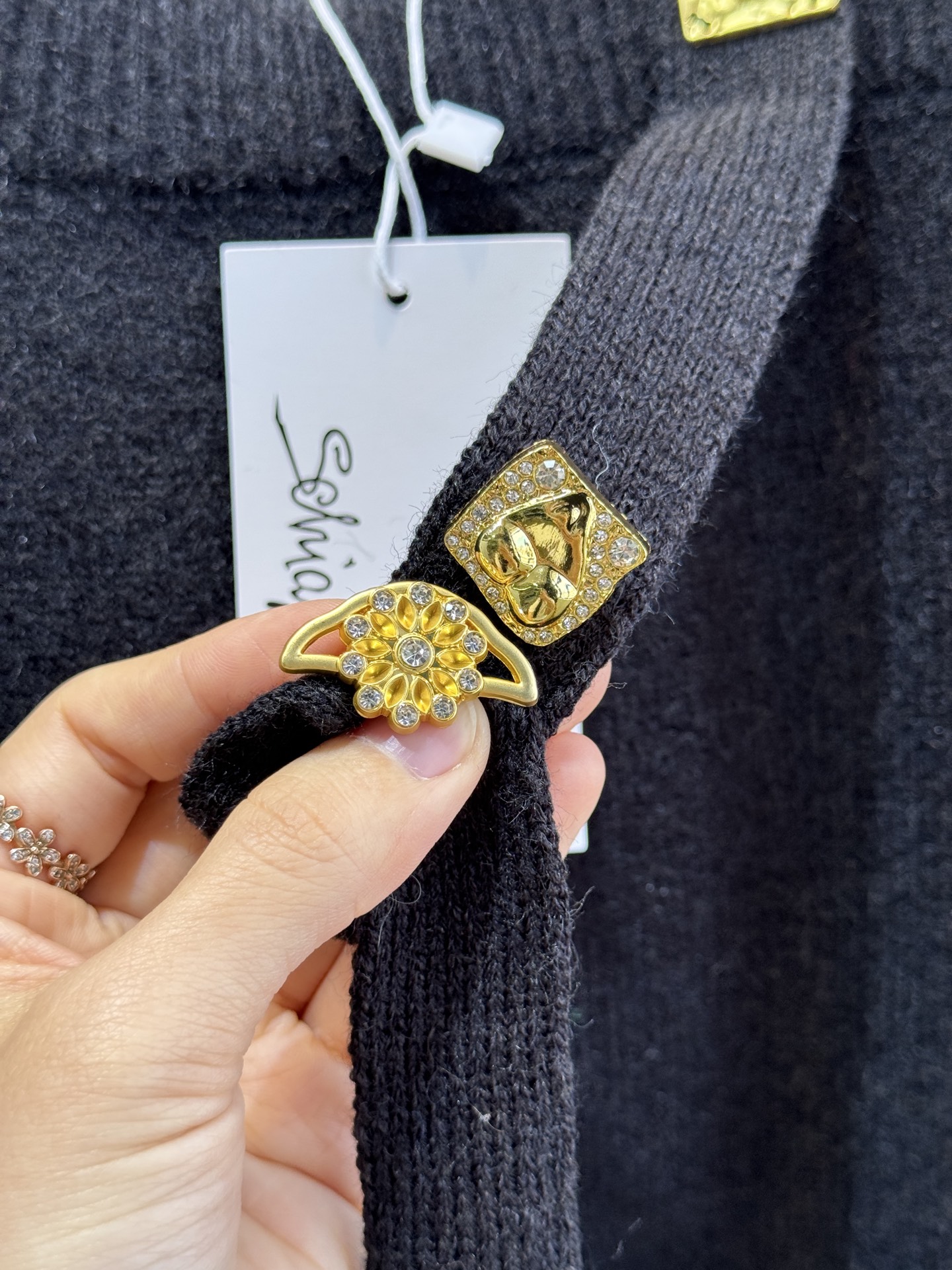 schiaparelli 侧纽扣设计的米白色针织衫短款版型，侧边采用斜排金属纽扣设计，兼具装饰性与实用性