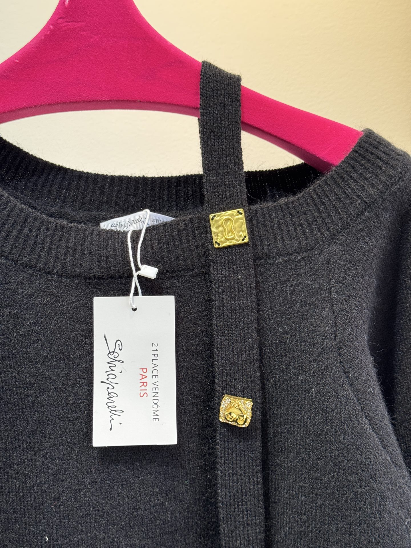 schiaparelli 侧纽扣设计的米白色针织衫短款版型，侧边采用斜排金属纽扣设计，兼具装饰性与实用性