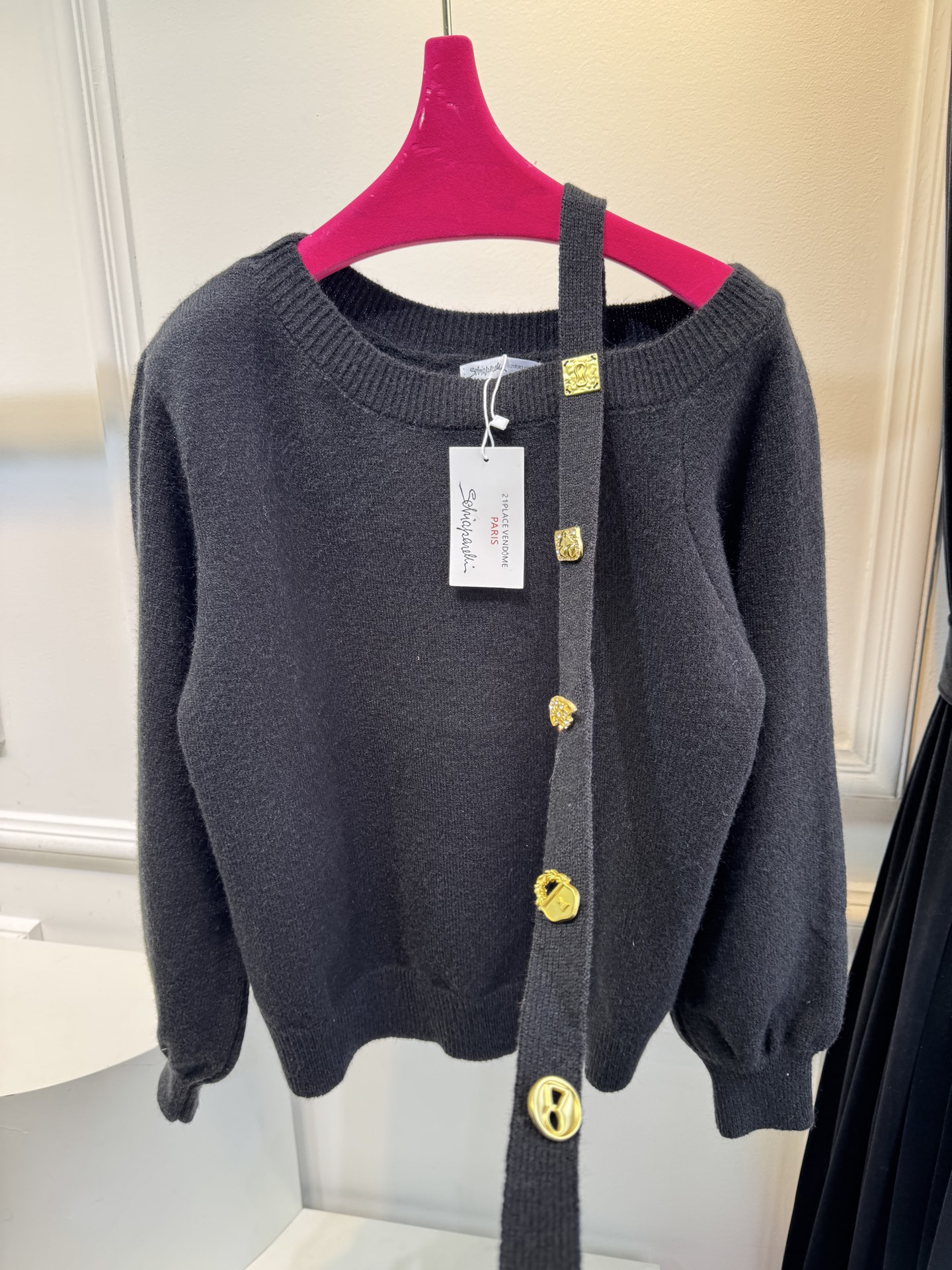 schiaparelli 侧纽扣设计的米白色针织衫短款版型，侧边采用斜排金属纽扣设计，兼具装饰性与实用性