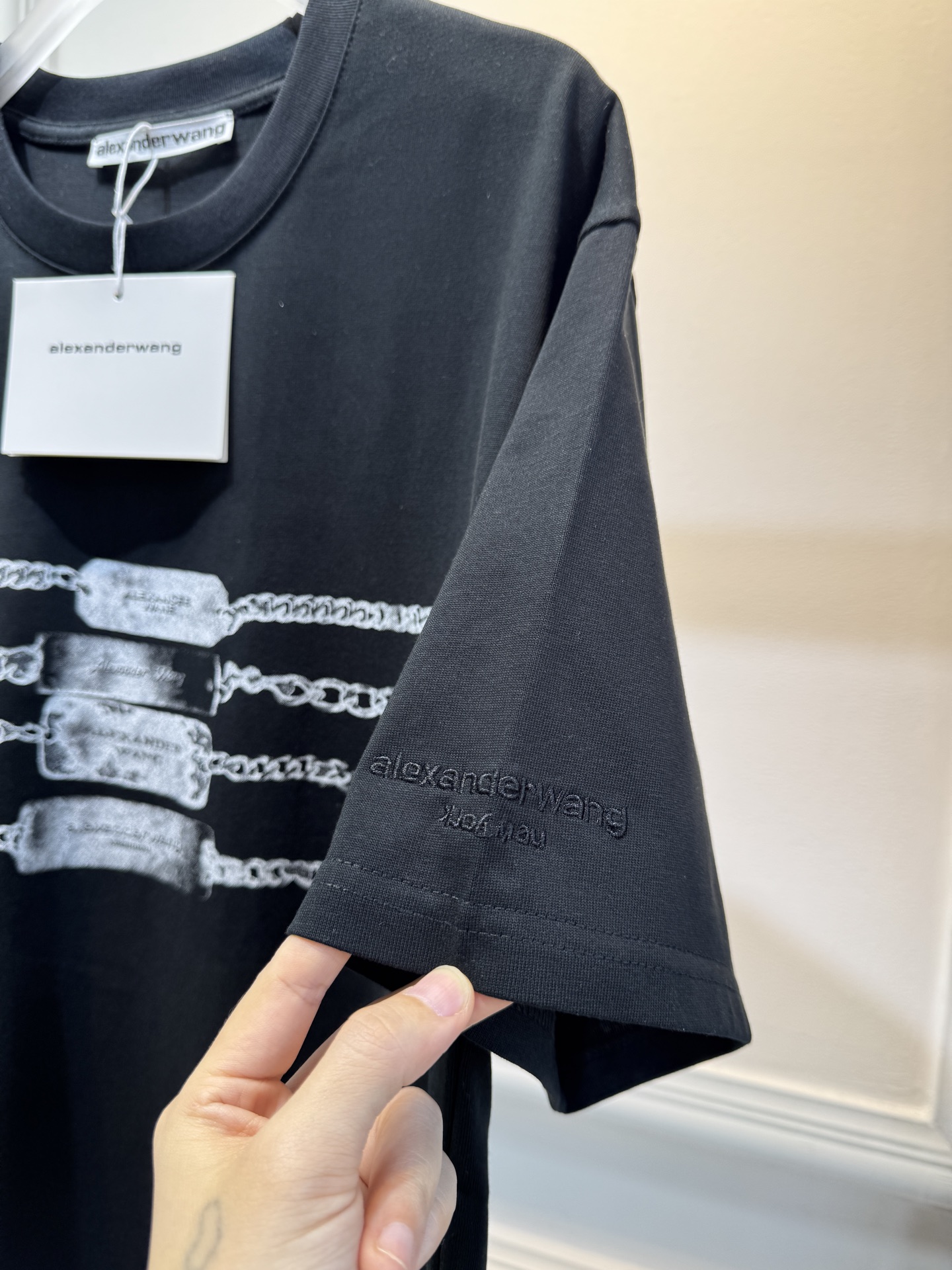 alexanderwang AW链条印花短袖T恤整体为宽松版型的基础款T恤，正面印有黑色链条+做旧金属牌