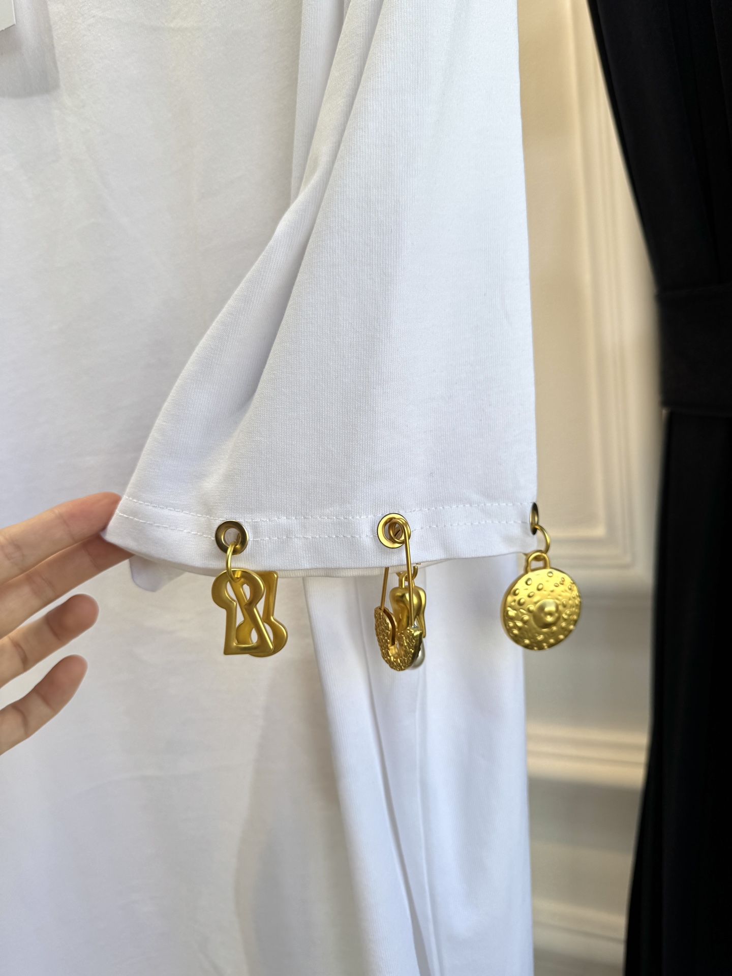 Schiaparelli（夏帕瑞丽）吊坠T恤采用oversize宽松圆领中袖版型，面料为柔软的棉质混纺，