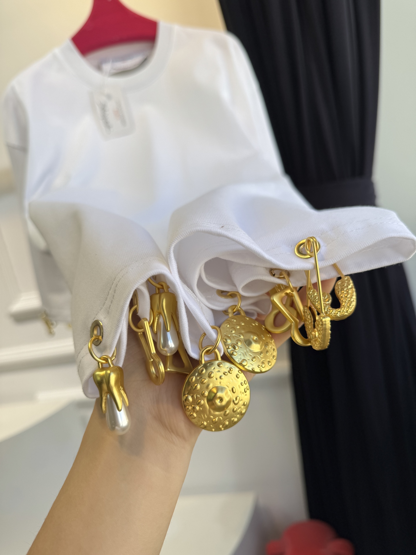 Schiaparelli（夏帕瑞丽）吊坠T恤采用oversize宽松圆领中袖版型，面料为柔软的棉质混纺，