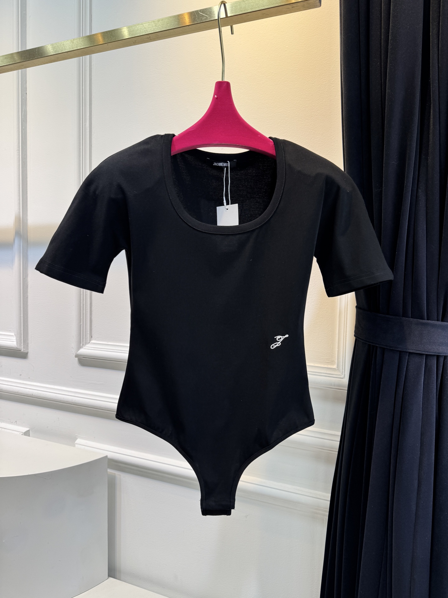 JACQUEMUS垫肩连体衣采用连体式的三角哈衣版型，搭配大U领与短袖设计，修身的剪裁能贴合身形，勾勒出