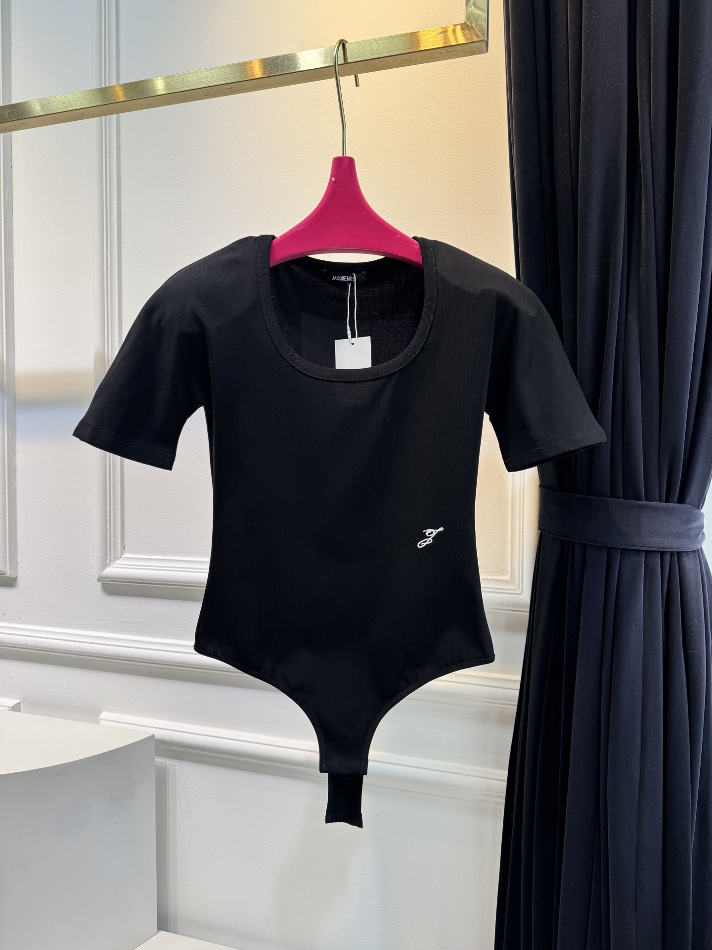 JACQUEMUS垫肩连体衣采用连体式的三角哈衣版型，搭配大U领与短袖设计，修身的剪裁能贴合身形，勾勒出