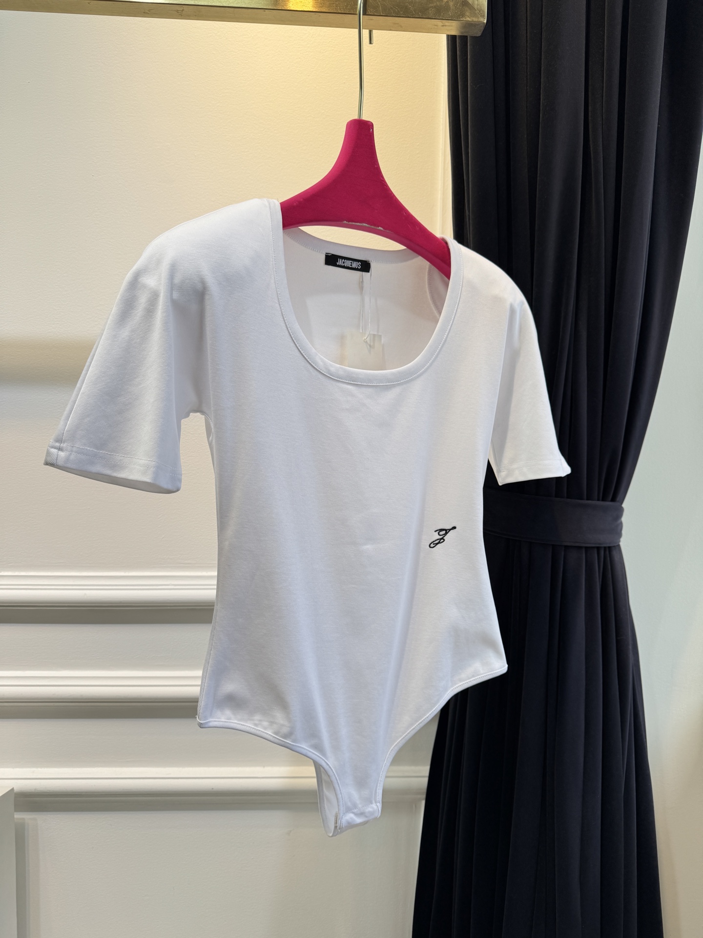 JACQUEMUS垫肩连体衣采用连体式的三角哈衣版型，搭配大U领与短袖设计，修身的剪裁能贴合身形，勾勒出