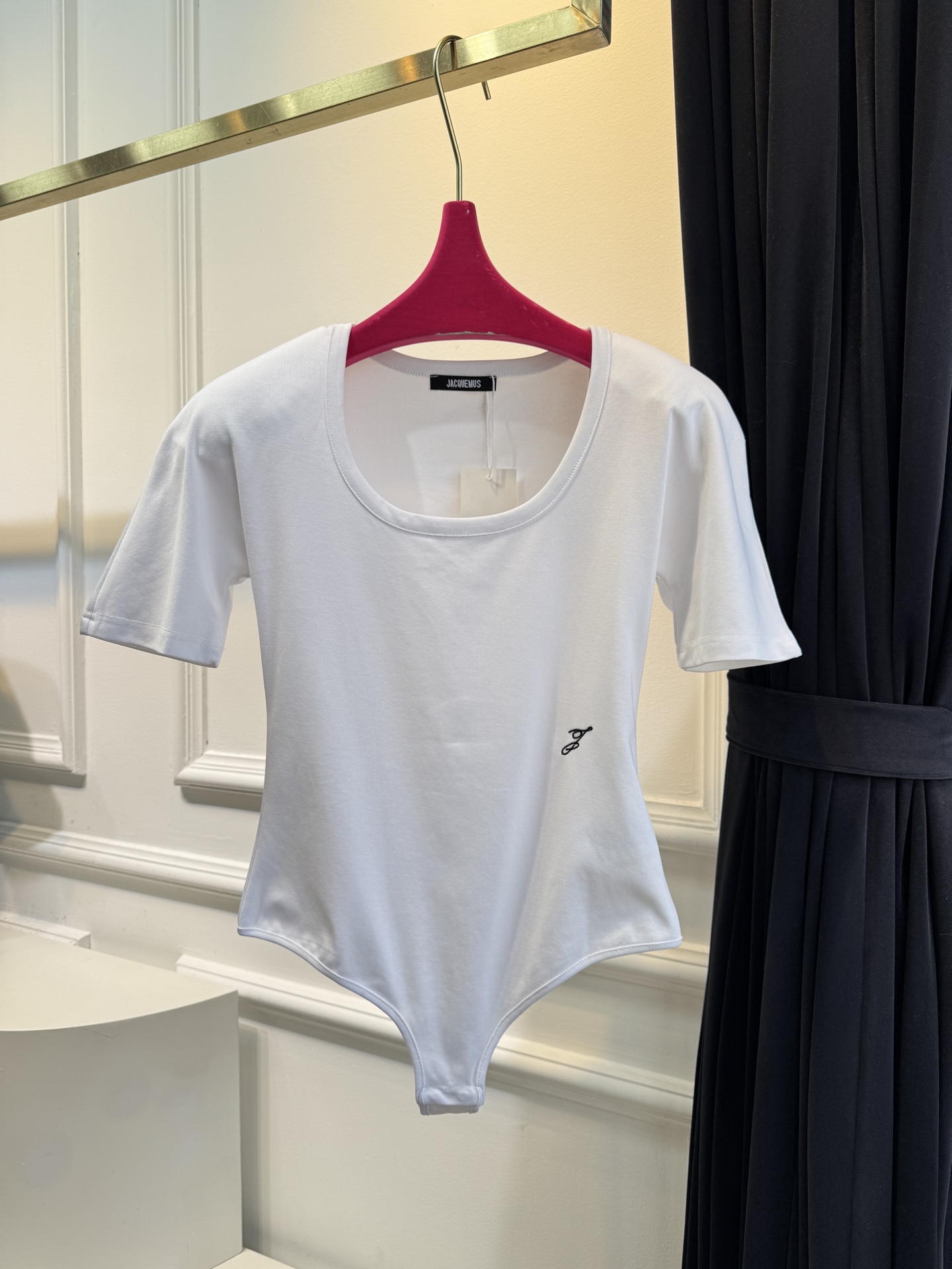 JACQUEMUS垫肩连体衣采用连体式的三角哈衣版型，搭配大U领与短袖设计，修身的剪裁能贴合身形，勾勒出