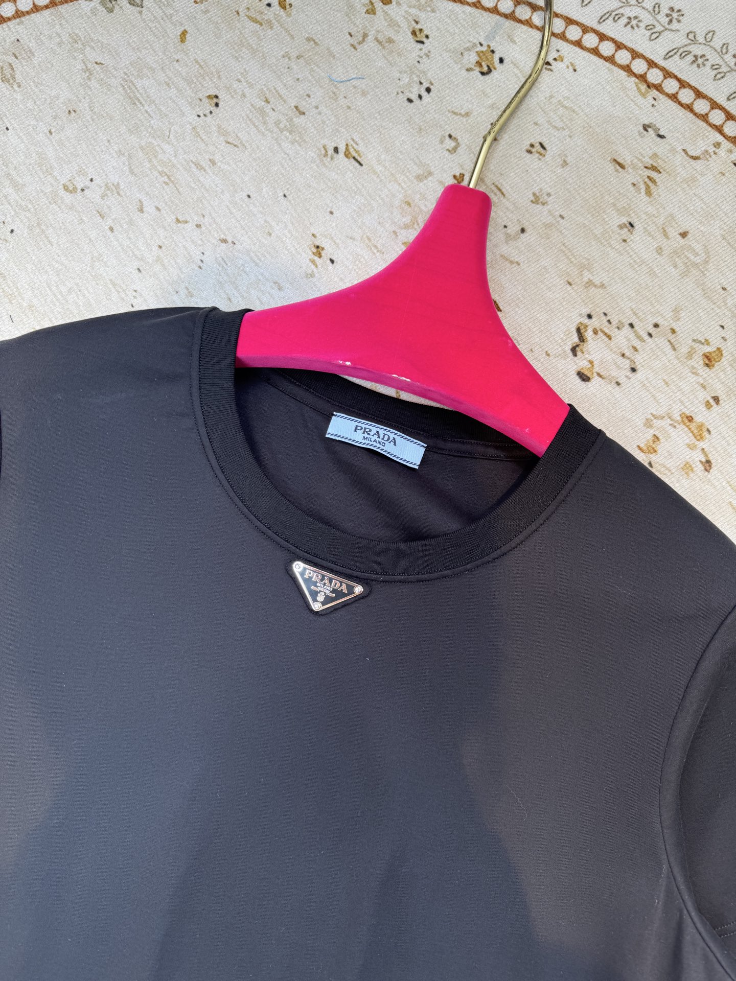 Prad*三角标圆领短袖T恤，胸前正下方的金属三角徽标是Prada的经典标识，采用品牌专属的金属材质与浮