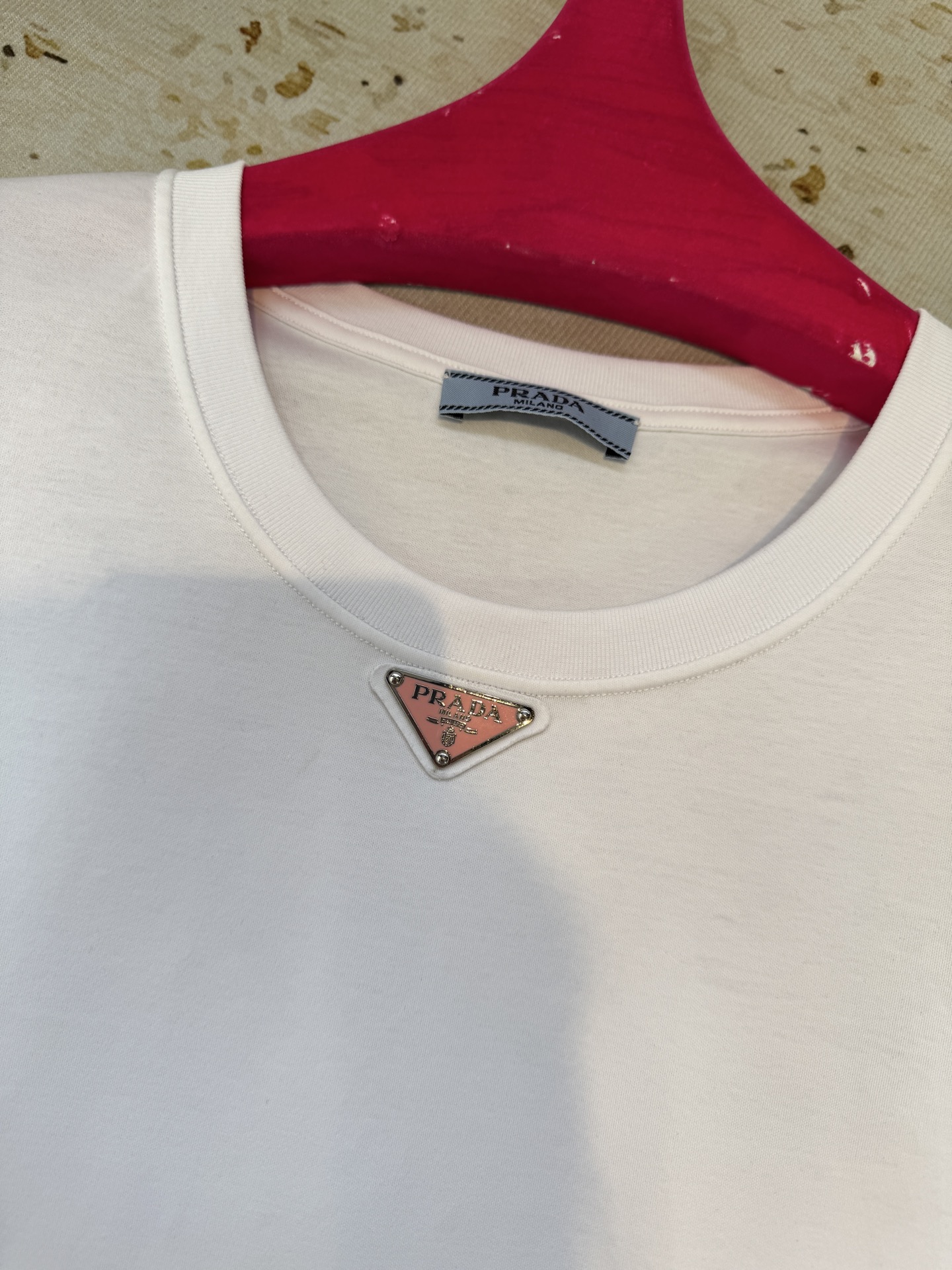 Prad*三角标圆领短袖T恤，胸前正下方的金属三角徽标是Prada的经典标识，采用品牌专属的金属材质与浮