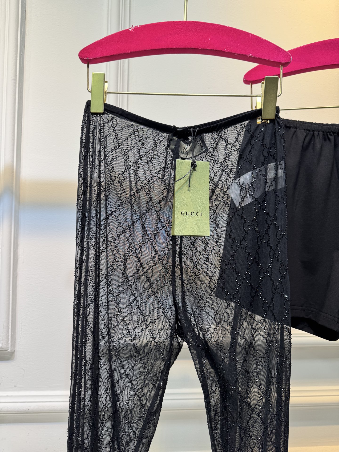 gucc* 饰GG仿水晶薄纱蕾丝紧身裤外层为深棕色蕾丝透视长裤，带有双G暗纹与烫钻点缀，裤脚处的双G烫钻