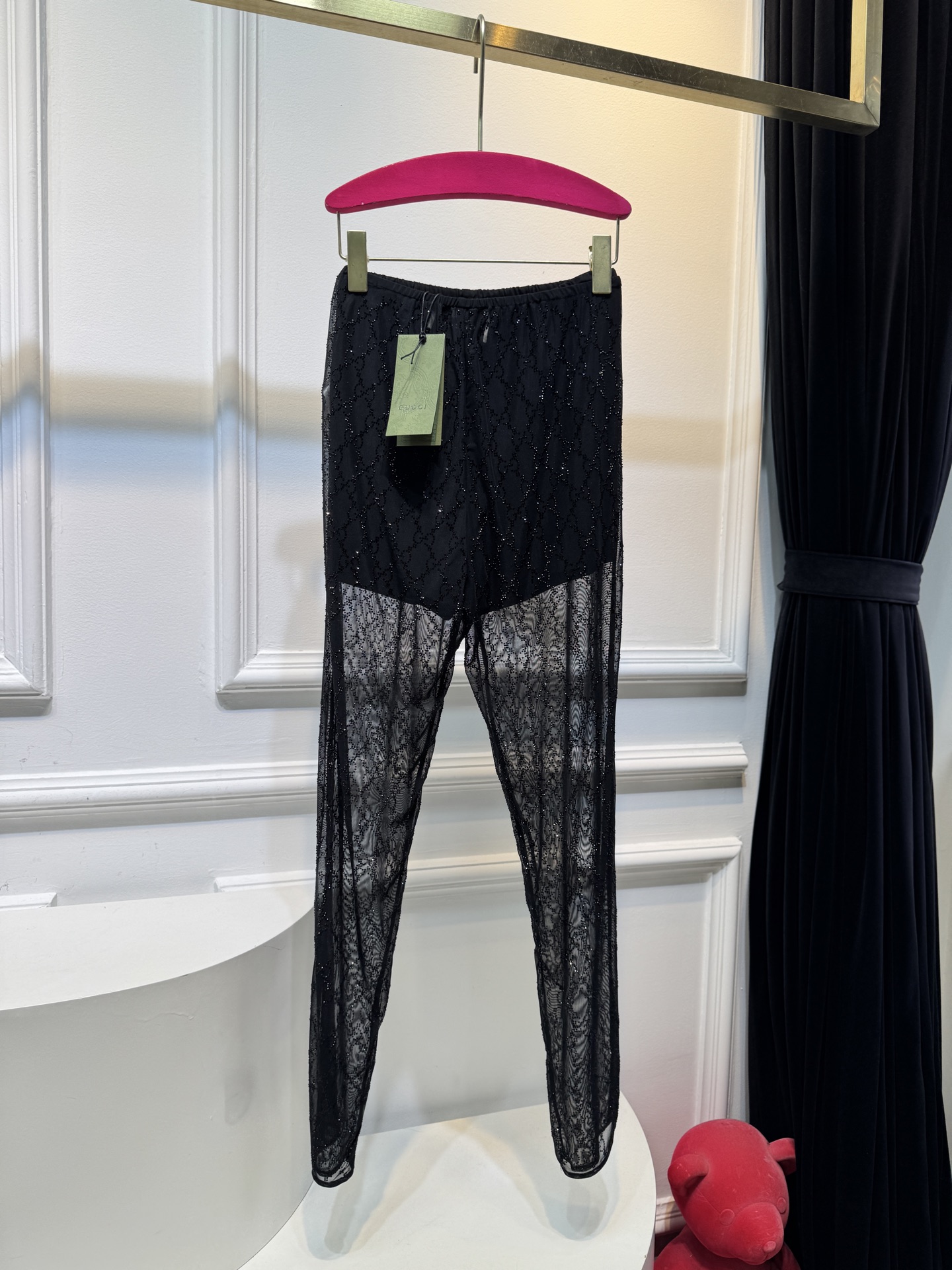 gucc* 饰GG仿水晶薄纱蕾丝紧身裤外层为深棕色蕾丝透视长裤，带有双G暗纹与烫钻点缀，裤脚处的双G烫钻