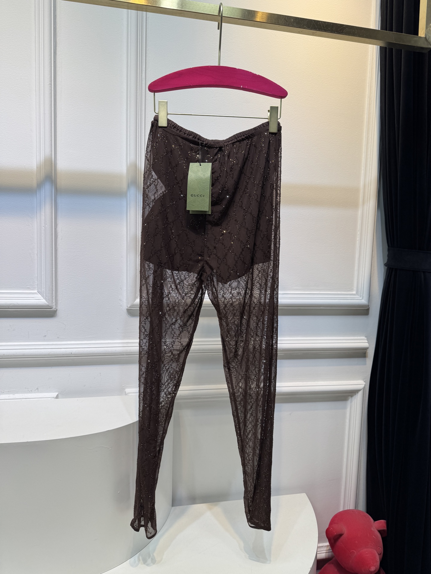 gucc* 饰GG仿水晶薄纱蕾丝紧身裤外层为深棕色蕾丝透视长裤，带有双G暗纹与烫钻点缀，裤脚处的双G烫钻