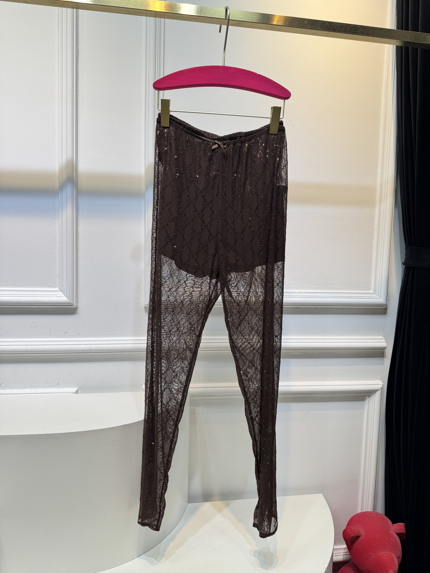 gucc* 饰GG仿水晶薄纱蕾丝紧身裤外层为深棕色蕾丝透视长裤，带有双G暗纹与烫钻点缀，裤脚处的双G烫钻