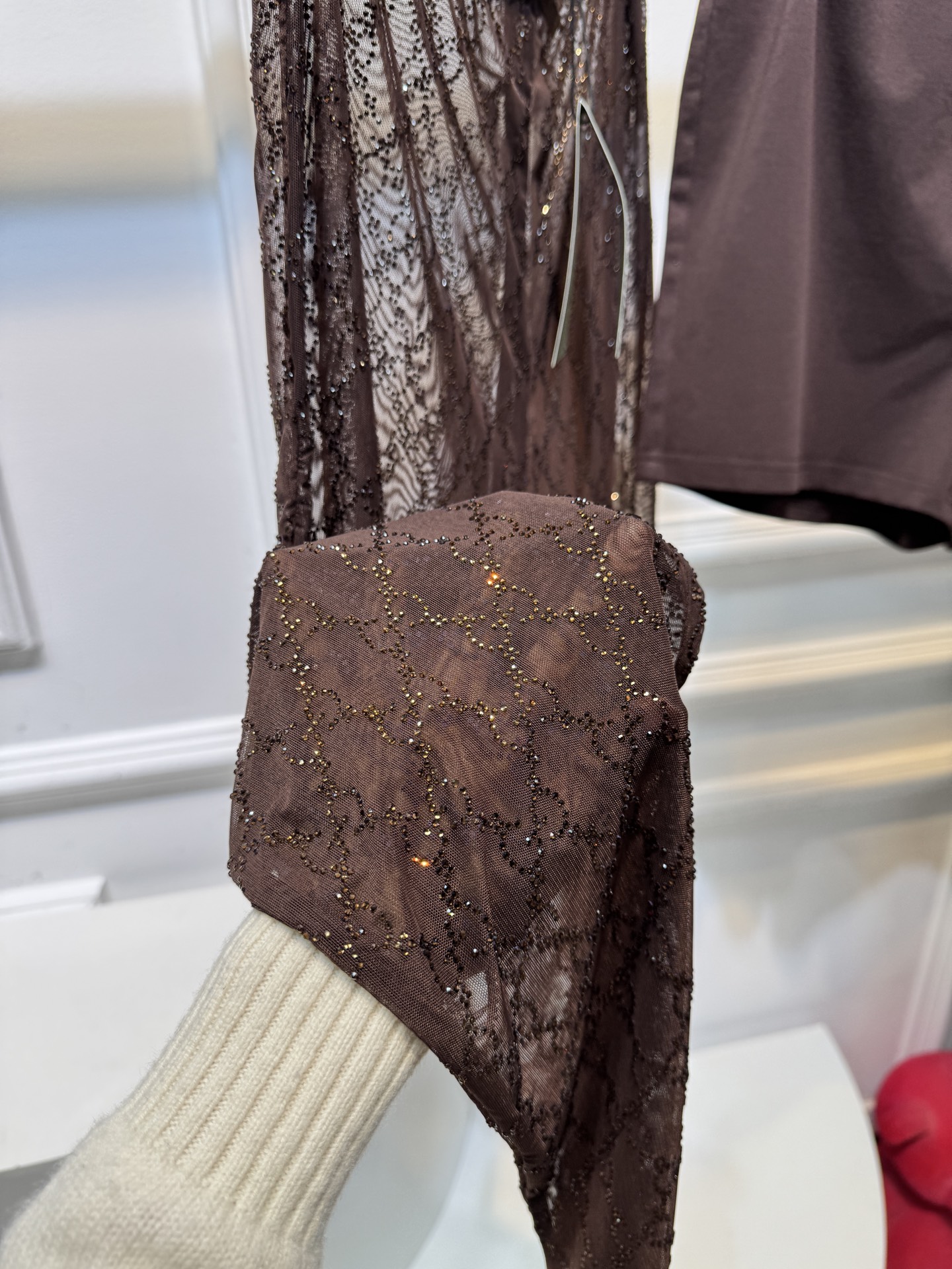 gucc* 饰GG仿水晶薄纱蕾丝紧身裤外层为深棕色蕾丝透视长裤，带有双G暗纹与烫钻点缀，裤脚处的双G烫钻