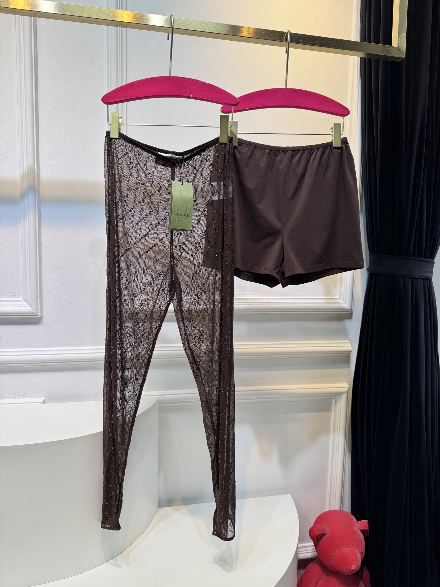 gucc* 饰GG仿水晶薄纱蕾丝紧身裤外层为深棕色蕾丝透视长裤，带有双G暗纹与烫钻点缀，裤脚处的双G烫钻