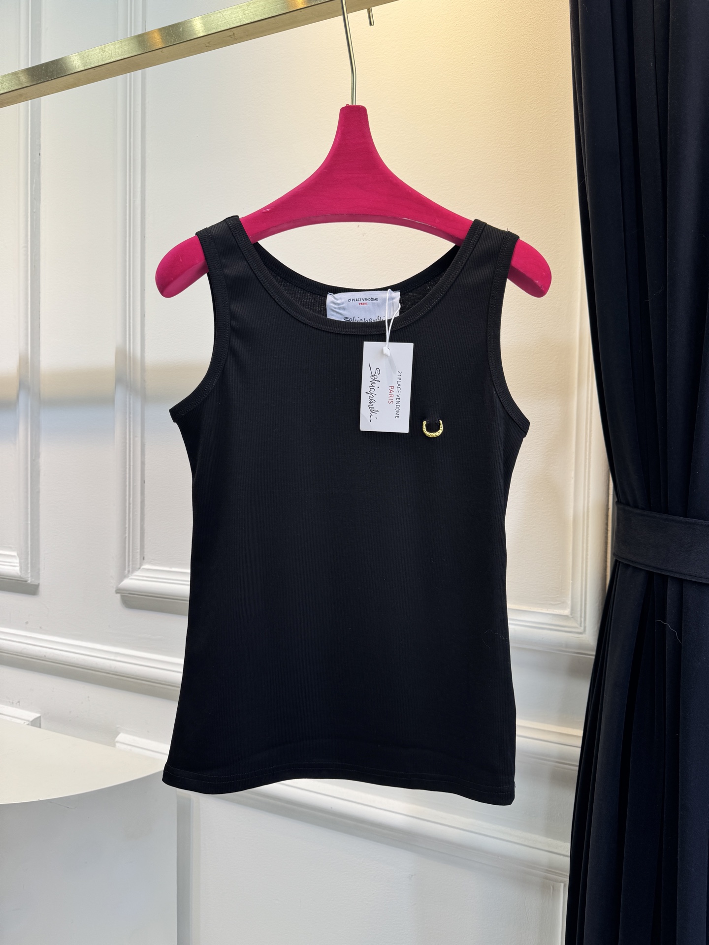 Schiaparelli（夏帕瑞丽）螺纹背心采用黑色罗纹针织面料，左胸处有标志性的金色月牙形金属装饰穿刺