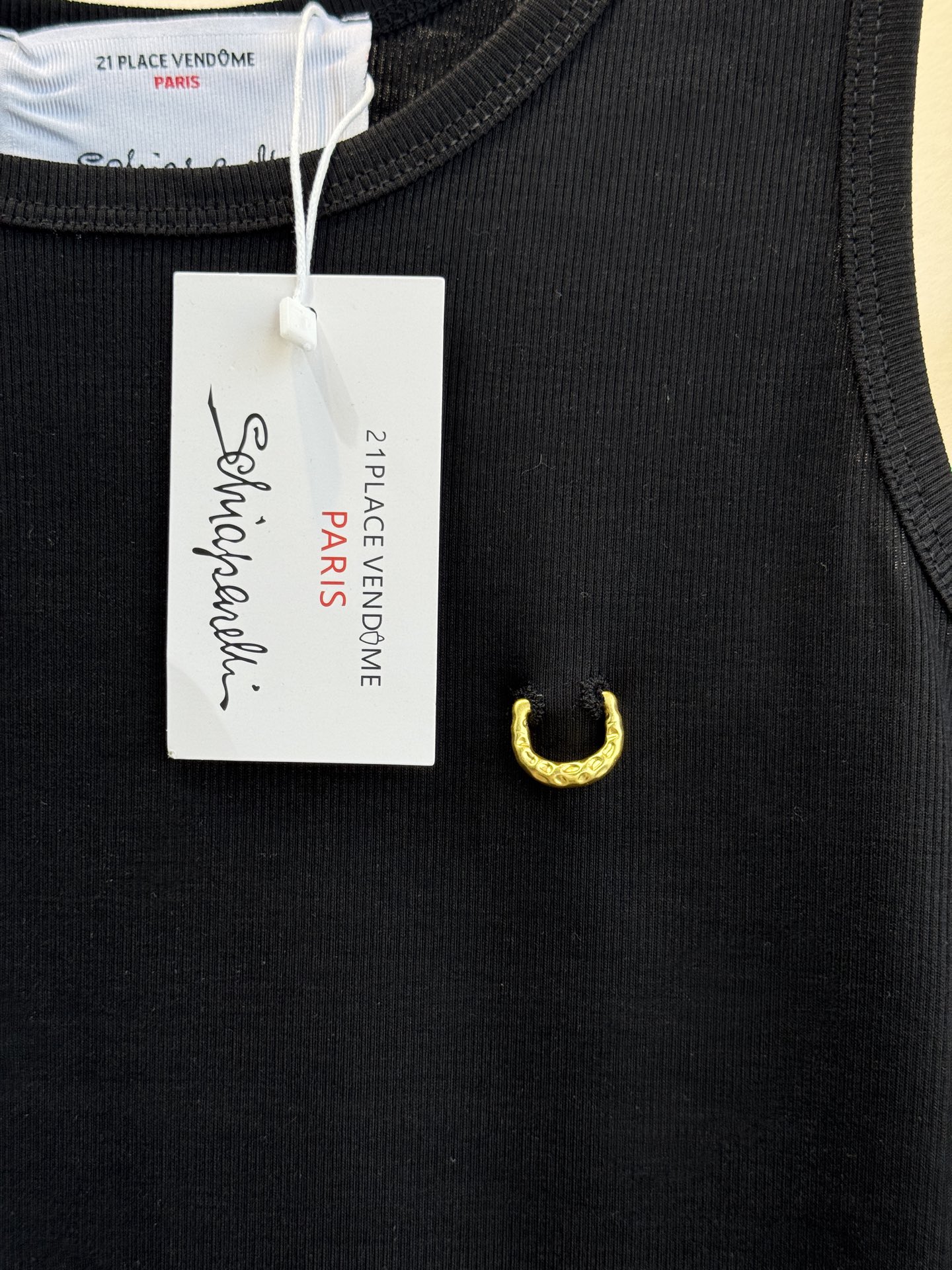 Schiaparelli（夏帕瑞丽）螺纹背心采用黑色罗纹针织面料，左胸处有标志性的金色月牙形金属装饰穿刺