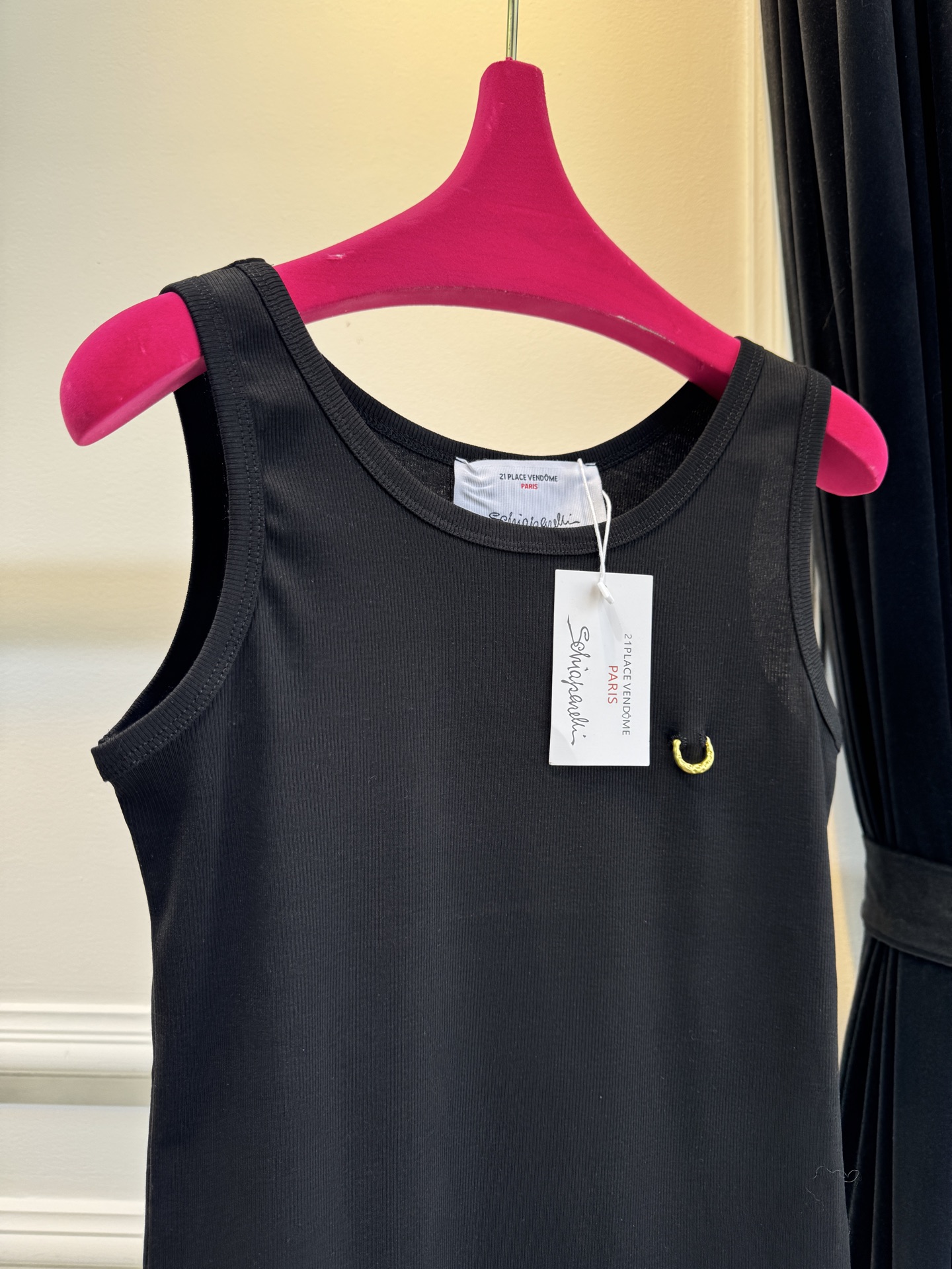 Schiaparelli（夏帕瑞丽）螺纹背心采用黑色罗纹针织面料，左胸处有标志性的金色月牙形金属装饰穿刺