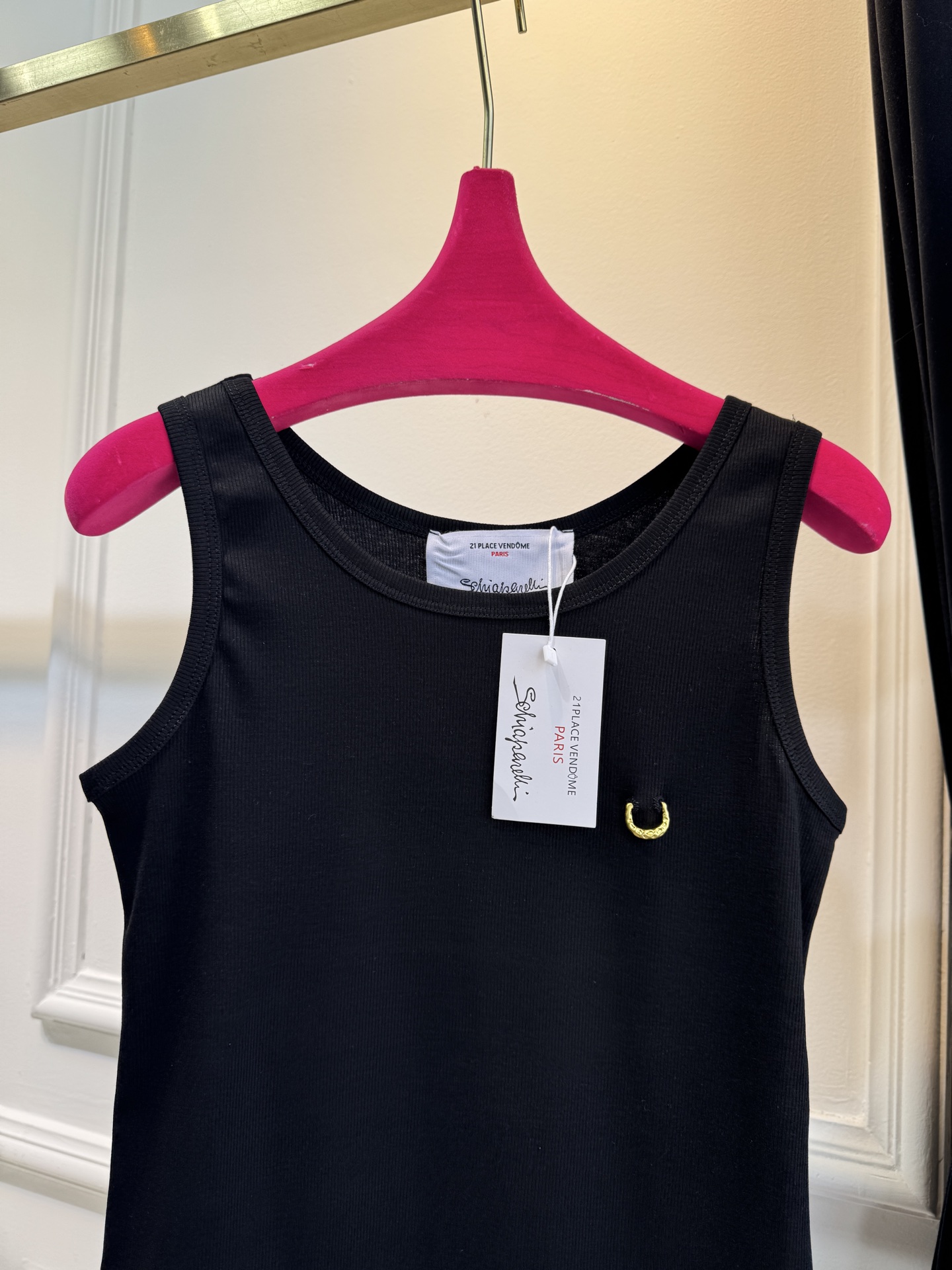 Schiaparelli（夏帕瑞丽）螺纹背心采用黑色罗纹针织面料，左胸处有标志性的金色月牙形金属装饰穿刺