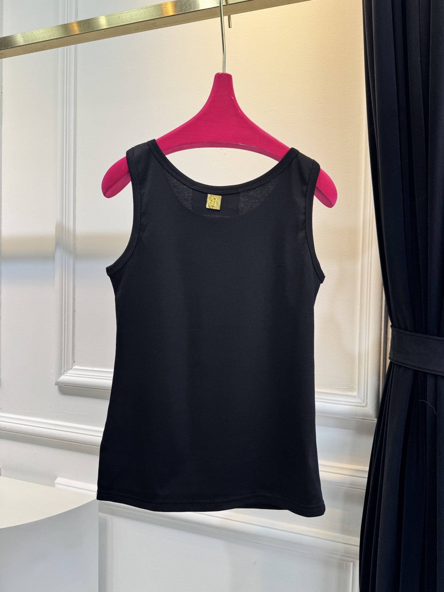 Schiaparelli（夏帕瑞丽）螺纹背心采用黑色罗纹针织面料，左胸处有标志性的金色月牙形金属装饰穿刺