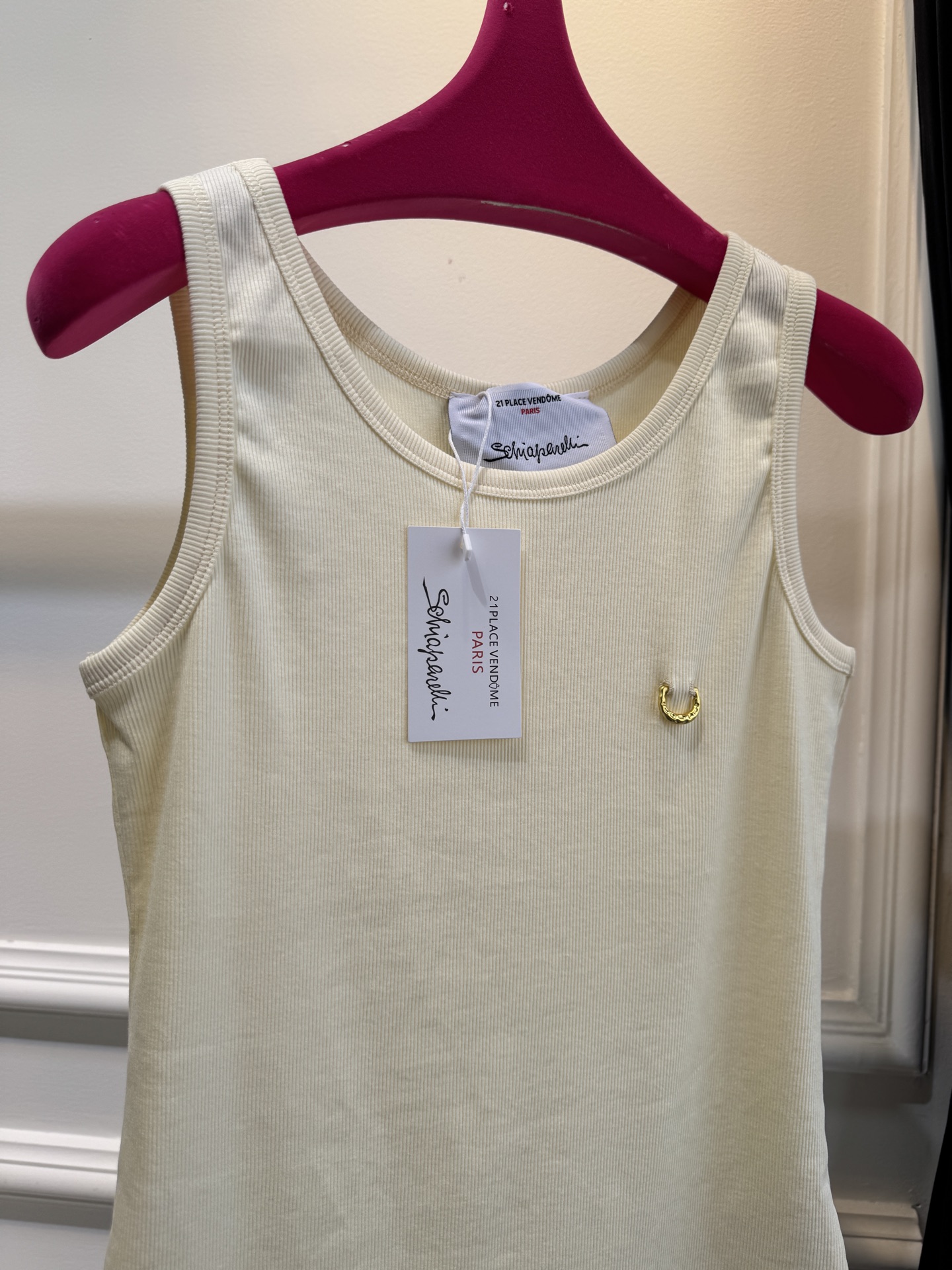 Schiaparelli（夏帕瑞丽）螺纹背心采用黑色罗纹针织面料，左胸处有标志性的金色月牙形金属装饰穿刺