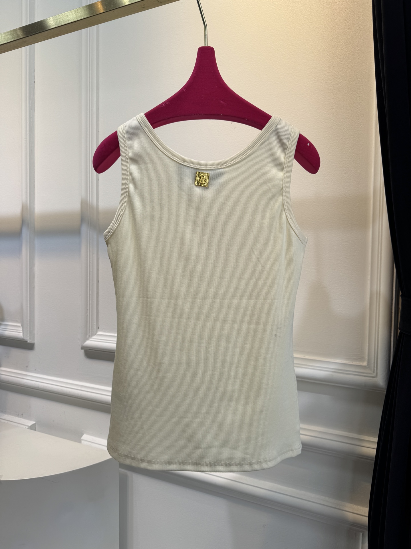 Schiaparelli（夏帕瑞丽）螺纹背心采用黑色罗纹针织面料，左胸处有标志性的金色月牙形金属装饰穿刺