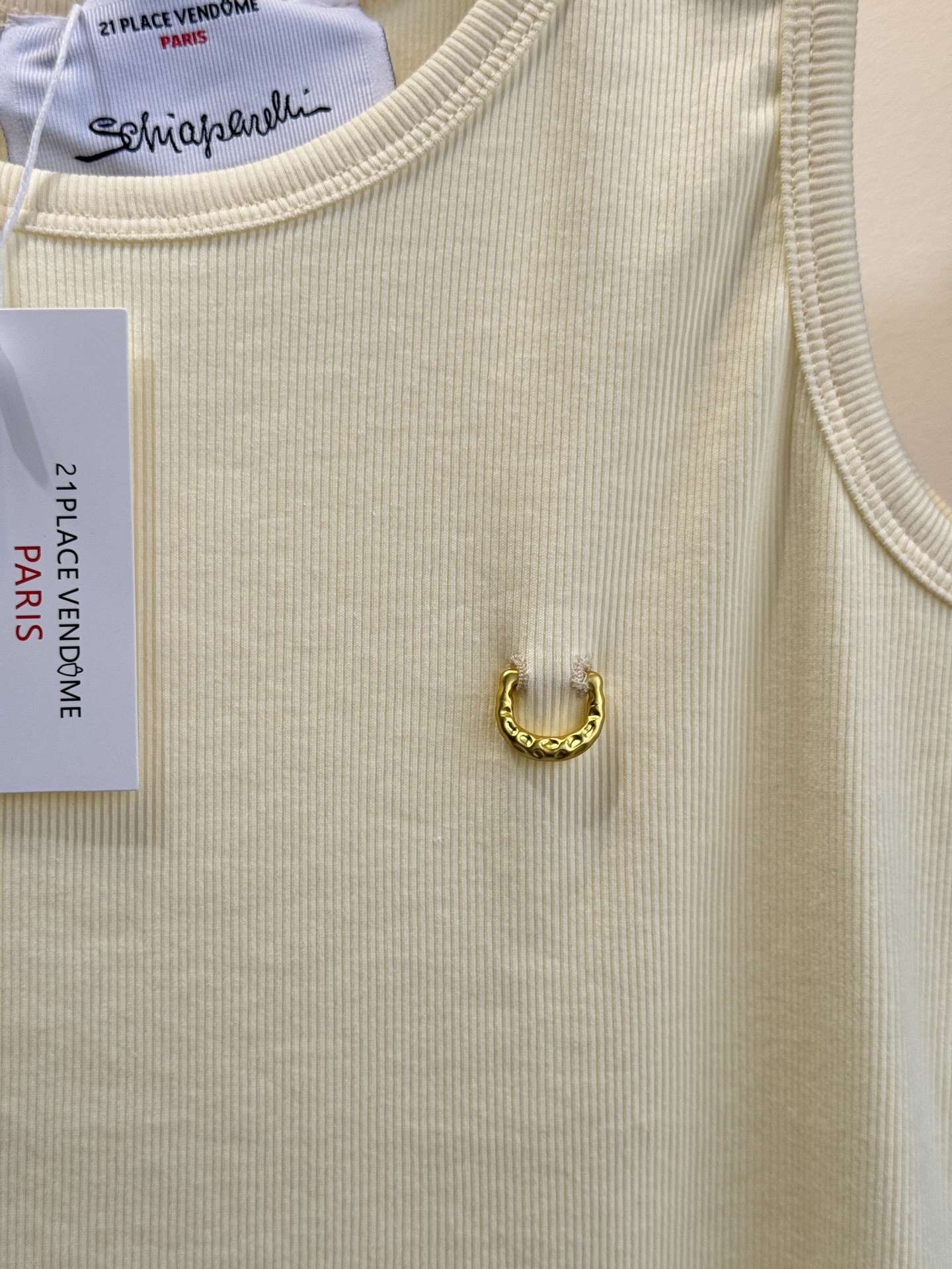 Schiaparelli（夏帕瑞丽）螺纹背心采用黑色罗纹针织面料，左胸处有标志性的金色月牙形金属装饰穿刺