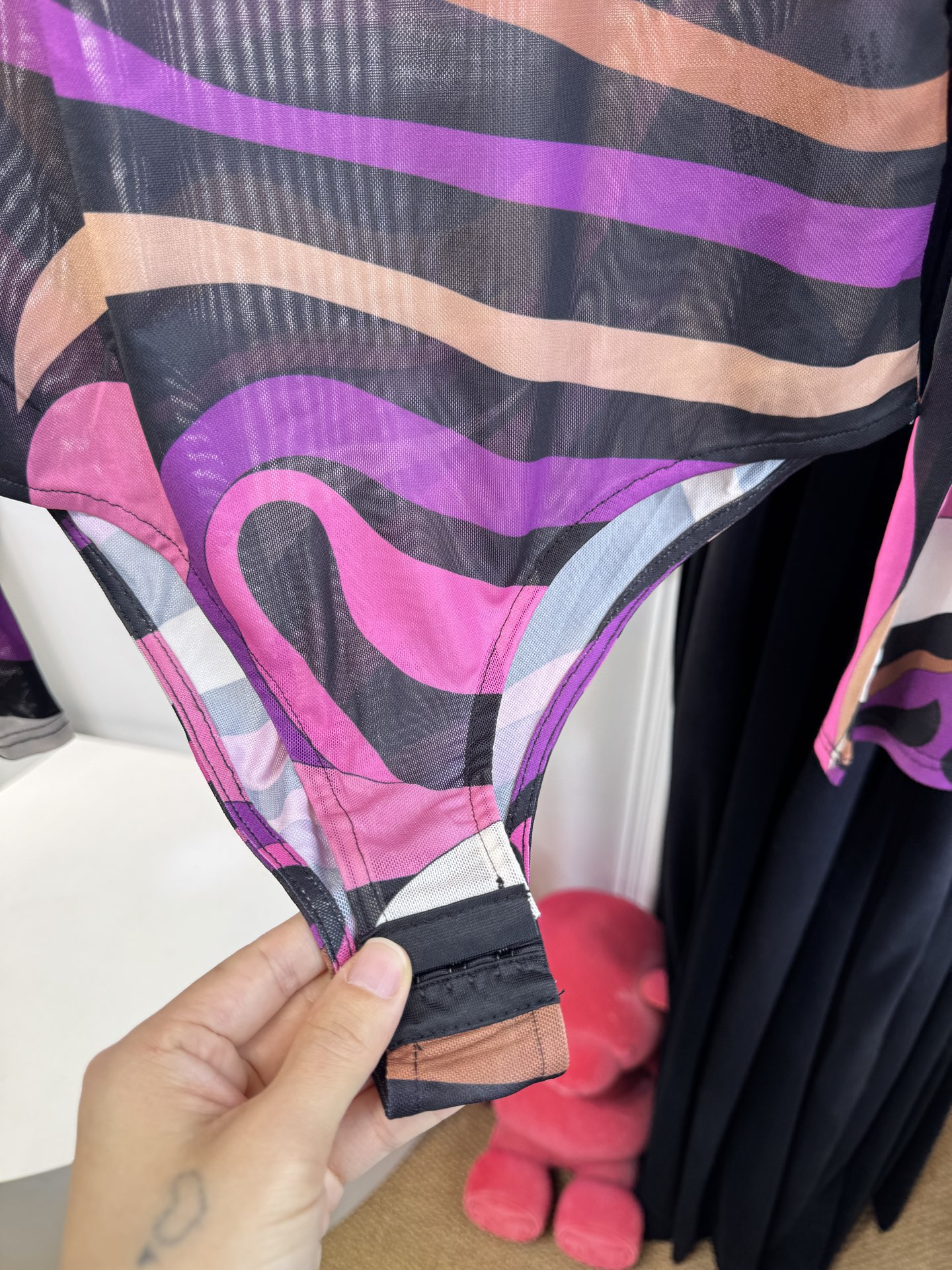 PUCCI 网纱连体衣图中采用的是品牌经典的 Marmo（大理石纹）/Iride 漩涡印花，也是Pucc