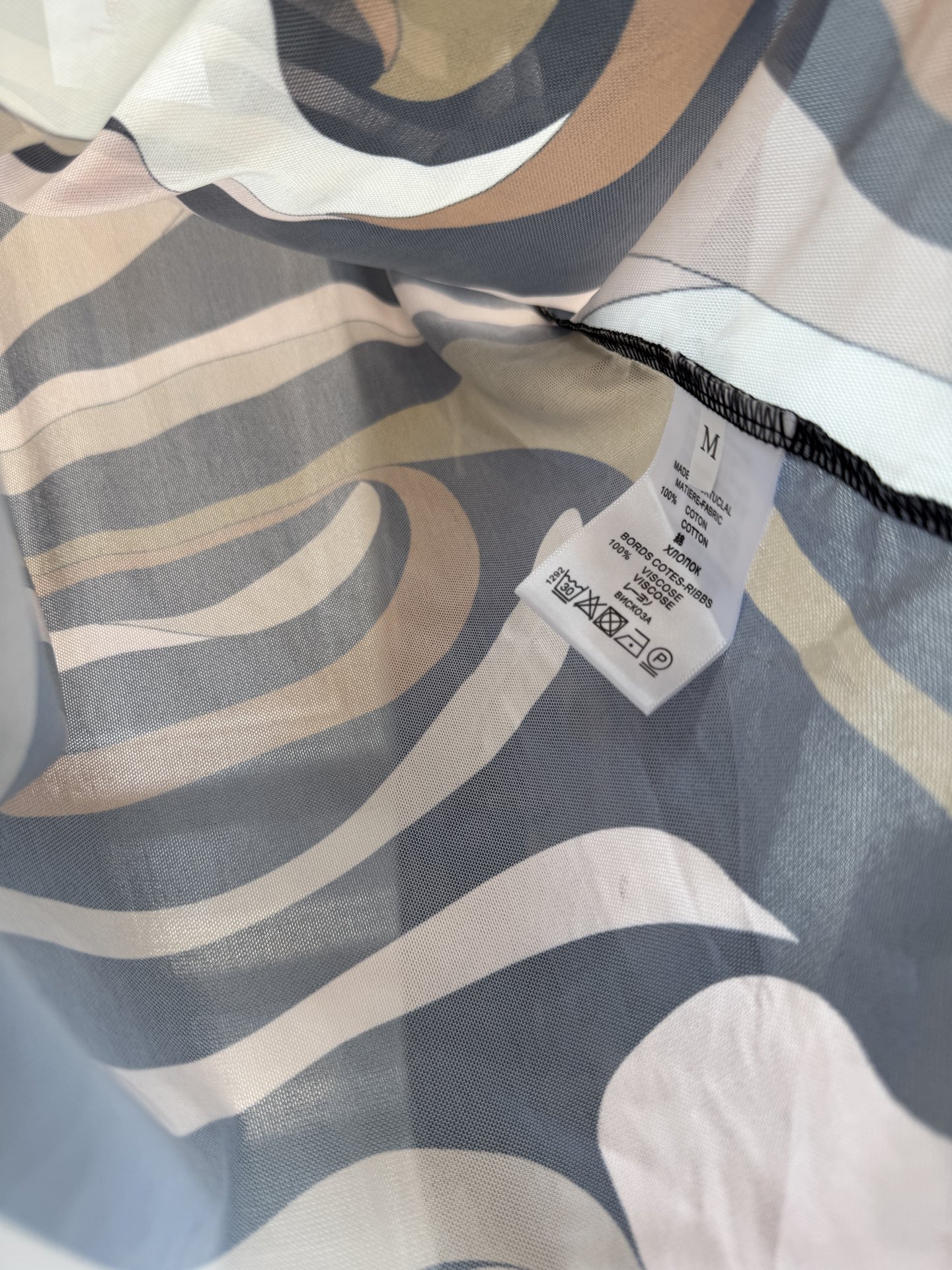 PUCCI 网纱连体衣图中采用的是品牌经典的 Marmo（大理石纹）/Iride 漩涡印花，也是Pucc