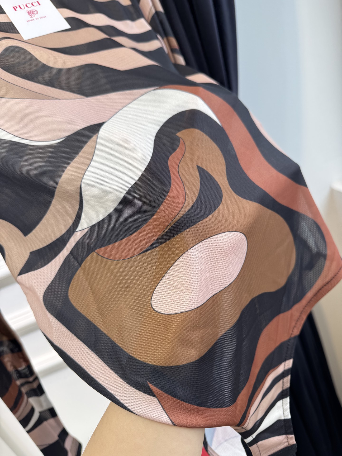 PUCCI 网纱连体衣图中采用的是品牌经典的 Marmo（大理石纹）/Iride 漩涡印花，也是Pucc
