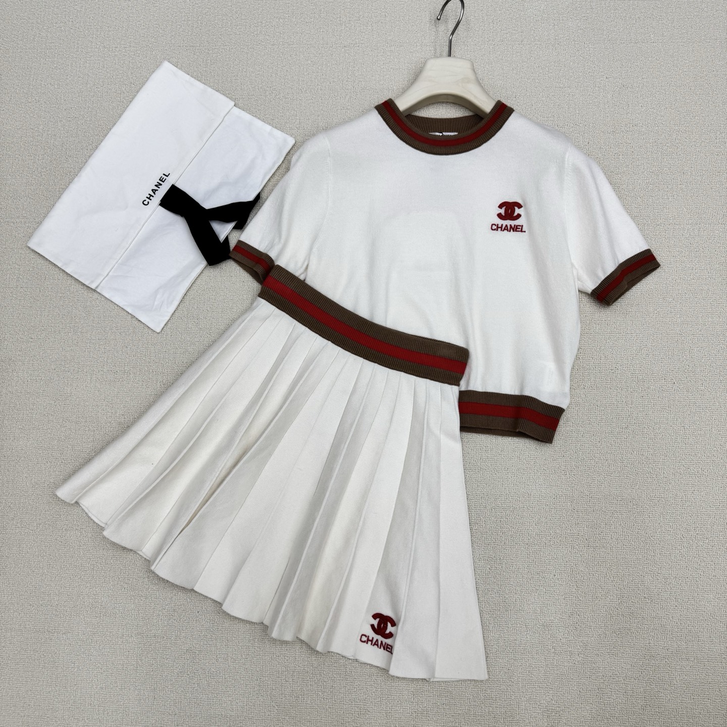 NO:803676,chan*26Ss new spring and summer style thread contrasting edge knitted short-sleeved + pleated skirt suit丨exclusively developed by yb!  Top quality production!  Virgin wool knitted fabric, comfortable and breathable. Contrast color knitted short round neck and short sleeves with threaded collar and cuffs, + high waist pleated skirt with contrasting letters. Lettering embroidery on the chest and hem matches the upper and lower parts. It has a low-key yet noble temperament. The upper and lower color-blocked threads not only add a sweet and cool design layer, but also highlight the brand atmosphere.  The pleated skirt uses neat pleats to outline girlish lines, and the short version raises the waistline, forming a perfect golden ratio with the short top, easily creating a playful and slim figure. Two colors are available for sale in stock S/M/L real shot details, chanel, skirts, T-shirt, gold,19860909chan*26Ss春夏新款 螺纹撞色边针织短袖+百褶半裙套装丨独家yb开发！顶级高版出品！初剪羊毛针织面料 舒适又透气 领口袖口螺纹撞色针织短款圆领短袖,+高腰撞色字母百褶半裙 胸前与下摆字母刺绣上下乎应 自带低调又不失高贵的气质 上下拼色螺纹既增添了甜酷的设计层次 又突显品牌气息 百褶半裙则以利落的褶裥勾勒出少女感线条,短款版型拉高腰线,与短款上衣形成完美的黄金比例,轻松打造俏皮又显瘦的身形.两色 现货发售S/M/L实拍细节图,,chanel,skirts,T-shirt,gold,,Women's clothing