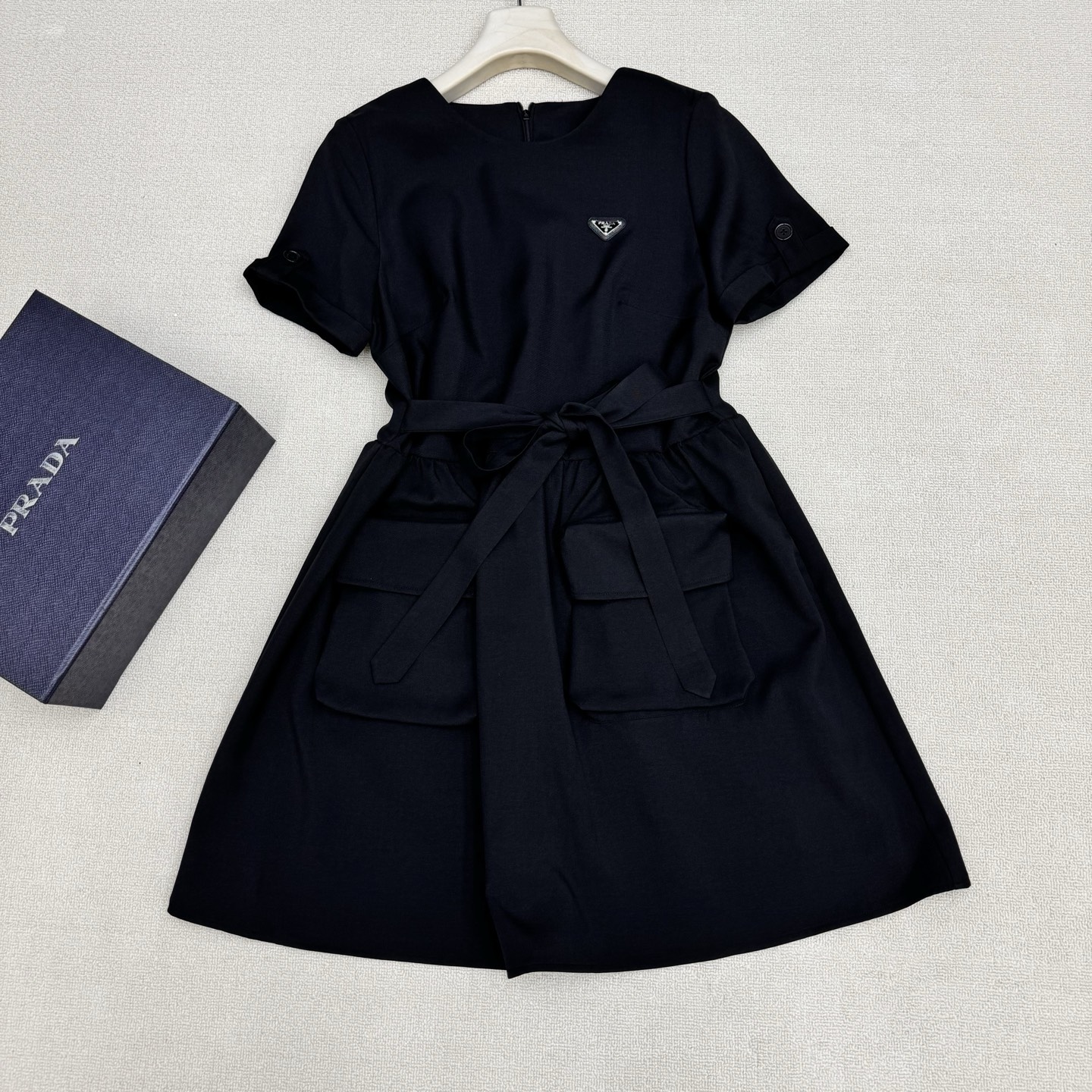 NO:807845,Prad* 26Ss spring and summer new style belted work dress丨exclusively developed by yb!  Top quality production!  Silk cotton fabric is comfortable and skin-friendly  The upper body feels soft and has a vertical texture. The classic triangular logo brand badge is low-key and cool, and it has a workwear-style cut with round neck + turned sleeves + large pockets. The extended zipper opening and closing design of the back panel takes into account the convenience of putting on and taking off and the change of shape. The stiletto waist design can freely tighten the waistline.  It outlines a neat X-shaped silhouette, weakens the lazy feeling of the loose version, and highlights the body proportions. It is a wardrobe finishing touch that combines design, practicality and individual style concepts. Two colors are available in stock, S/M/L, real shot details, prada, skirts,19860909Prad* 26Ss春夏新款 束腰挷带工装连衣裙丨独家yb开发！顶级高版出品！丝质棉面料舒服亲肤 手感软糯上身自带垂直质感,经典三角标品牌胸章低调且不失贵气千金的酷酷感,圆领+翻袖+大口袋的工装风剪裁,后片加长拉链开合设计兼顾穿脱便利与造型变化,挷带腰设计能自由收束腰线,勾勒出利落的X型廓形,弱化宽松版型的慵懒感,凸显身形比例.是一件兼具设计感、实穿性与个性风格理念的衣橱点睛之选.两色现货发售S/M/L实拍细节图,,prada,skirts,,Women's clothing
