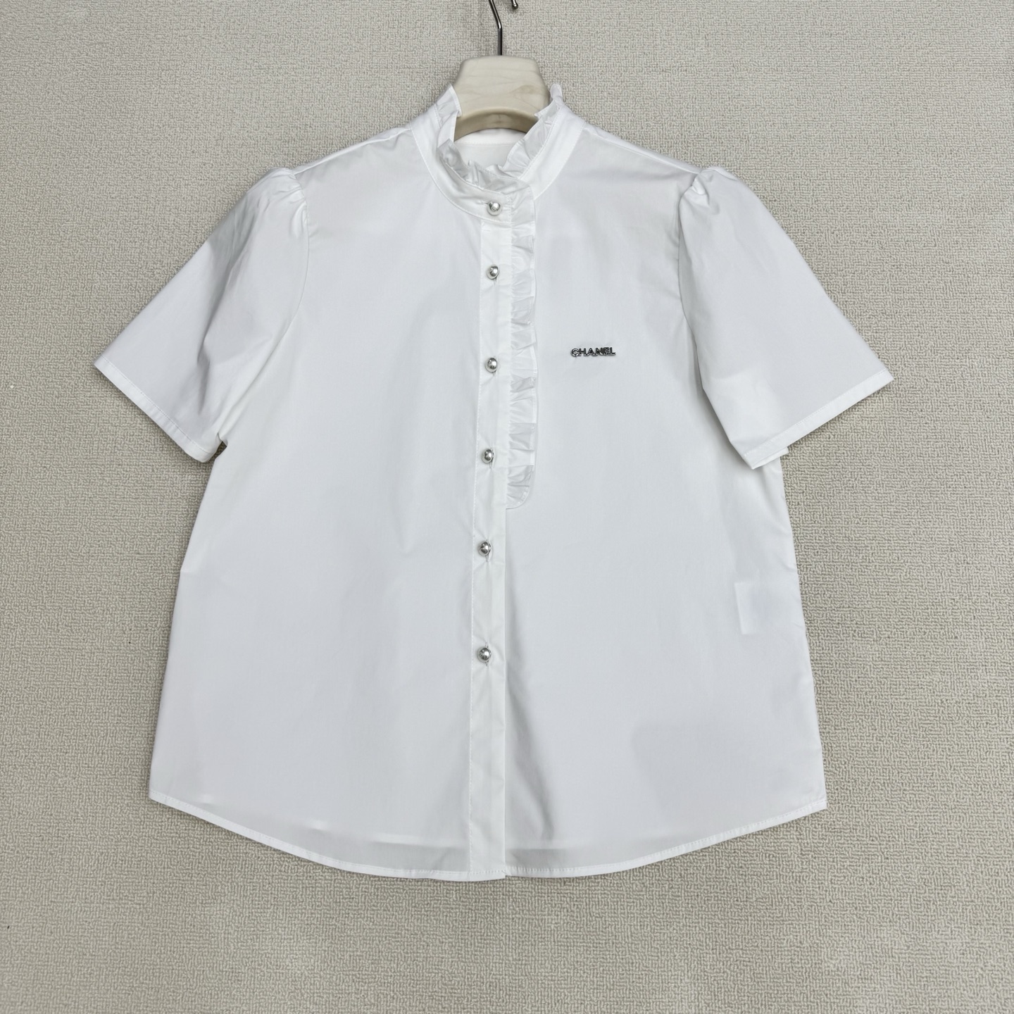 NO:807857,chan**26Ss new spring and summer fungus college style short-sleeved shirt丨exclusively developed by yb!  Top quality production!  The custom-made molded hardware letter badge is the finishing touch of the brand. The solid white and pink gentle lace outlines a sweet college feel. The high-count cotton fabric is breathable and skin-friendly. The crisp version hides small fat. The chest Logo hardware logo + double C engraved pearl breast buttons.  Low-key declaration of noble status, whether it is a sweet girl style with a pleated skirt, or a light and mature look with a suit, it can be easily controlled. This shirt is the most understanding girl's heart in spring. Two colors are available in stock, S/M/L real shot details, chanel, skirts, shirts, T-shirt, business suit,19860909chan**26Ss春夏新款木耳边学院风短袖衬衫丨独家yb开发！顶级高版出品！订制开模五金字母胸章为品牌的点睛之笔,纯色系白色粉色温柔花边勾勒出甜美学院感,高支棉面料透气亲肤,挺括版型藏住小赘肉,胸口Logo五金标识+双C刻字珍珠排扣 低调宣告贵气身份,无论是配百褶裙的甜妹风,还是搭西装的轻熟感,都能轻松驾驭.这件衬衫,是春天里最懂少女心的存在.两色现货发售S/M/L实拍细节图,,chanel,skirts,shirts,T-shirt,business suit,,Women's clothing