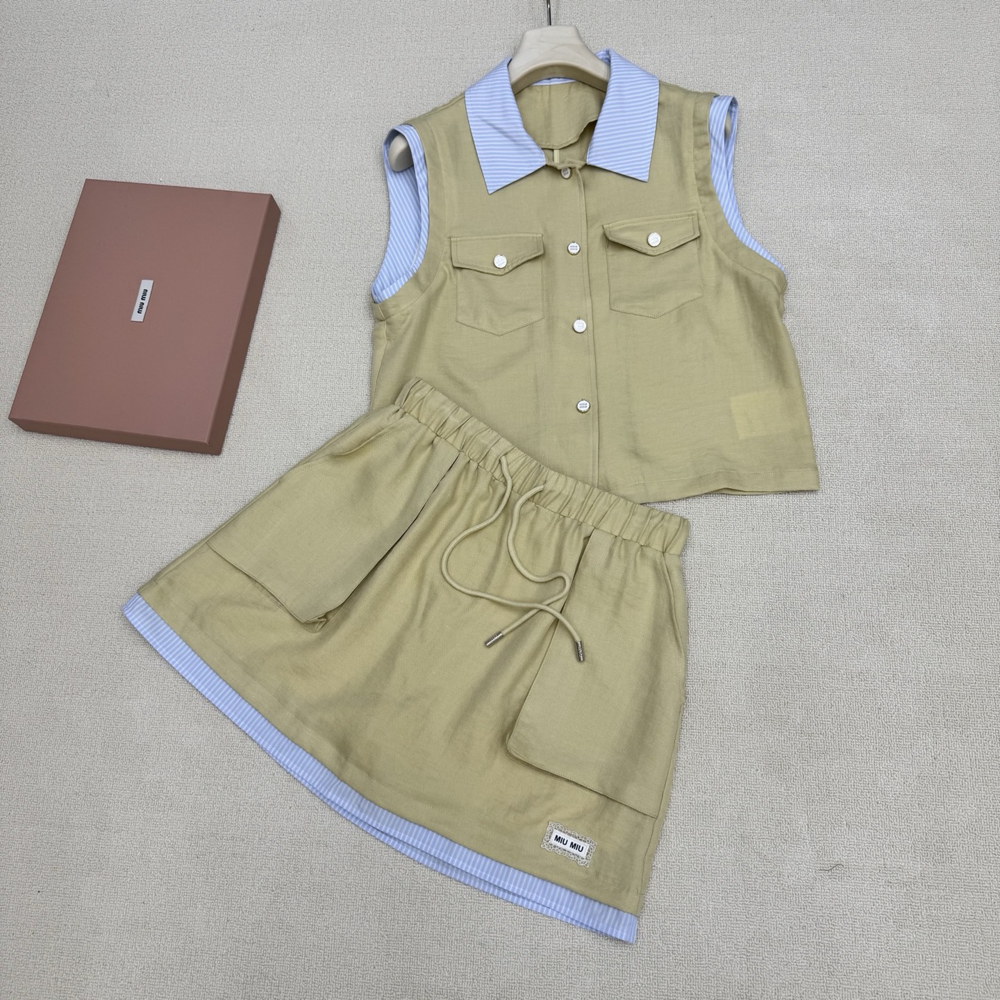 NO:808396,miumi*26Ss new spring and summer polo collar sleeveless shirt + drawstring work skirt set丨Exclusive high-end version!  Minimalist and relaxed workwear-style suit, casual healing suit, shirt spliced with contrasting collar design + elastic waist skirt hem with contrasting splicing upper and lower to match. It is a very suitable suit for summer. Breathable silk and cotton blend material. The hem brand micro-label is a poke point + patch workwear large pocket. Wearing it casually exudes a bit of 'artistic elegance' and just reveals the original 'slow' attribute.  ,Two colors ready for sale S/M/L real shot details,,miumiu,skirts,shirts,19860909miumi*26Ss春夏新款 polo领无袖衬衫+抽绳工装半裙套装丨独家高版出品！极简松弛感拉满工装风套装 随性治愈系套装 衬衫拼接撞色领设计+松紧腰半裙下摆撞色拼接上下成套相呼应.夏天穿很合适的套装 自带呼吸感的丝质棉伦混纺材质 下摆品牌微标为戳点+贴片工装大口袋 随便一套一穿就散发着几分“文艺贵” 恰到好处的透露着原生的“慢”属性 ,两色现货发售S/M/L实拍细节图,,miumiu,skirts,shirts,,Women's clothing