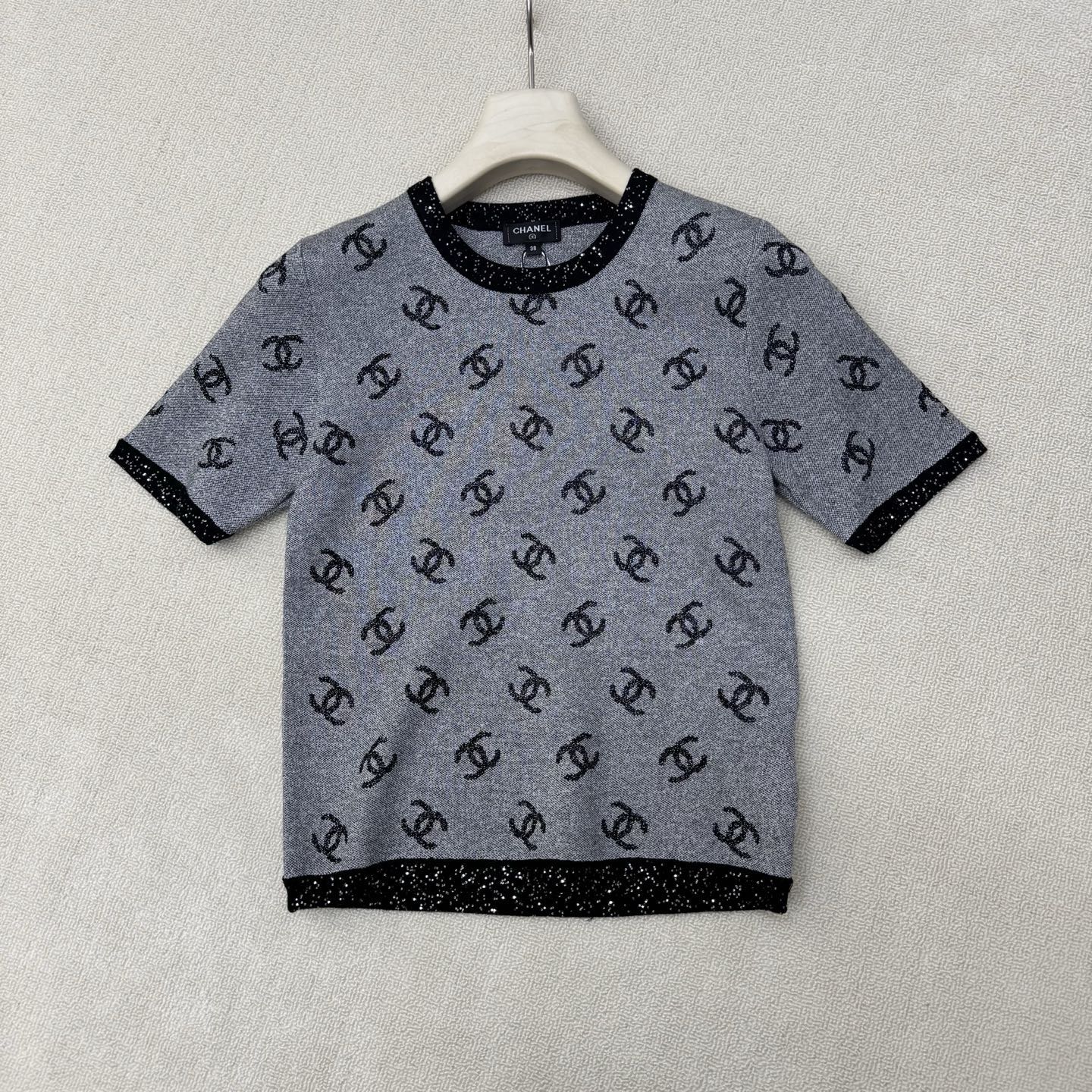 NO:858849,Chane*26 new summer style knitted round-neck short sleeves. The iconic double C pattern meets exquisite knitting technology. The silver-gray body is full of low-key and luxurious double C elements. Just like the twinkling stars in the night sky. Every glimmer embodies the brand's profound heritage. The black trim outlines the collar and cuffs, adding a refined sense of layering to the overall look. Ready for sale in size 363840, chanel, T-shirt,19860909Chane*26夏季新款针织圆领短袖 标志性的双C图案遇上精致的针织工艺 银灰色的衣身布满低调又奢华的双C元素 恰似夜空中闪烁的星辰 每一处微光都凝聚着品牌的深厚底蕴 黑色镶边勾勒领口与袖口 为整体造型增添了精致的层次感 现货发售尺码363840,,chanel,T-shirt,,Women's clothing