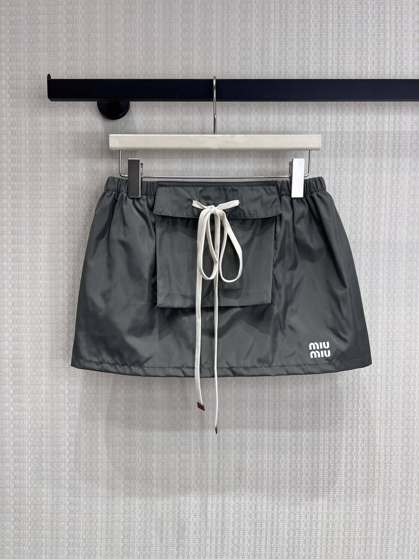 NO:858921,26 new spring and summer Mi** dark gray nylon drawstring work style mini skirt. The 'Y2K Retro Revival' skirt for sweet and cool girls is here. High-definition nylon fabric comes with a soft light filter, dark gray tone is high-end and stain-resistant. Large front pocket + contrasting off-white drawstring, which combines the neatness and girlishness of the work style. Low-waisted micro-A version, easy to wear to look like a hot girl. Exquisite logo printing on the side, low-key and recognizable.  Wearing a sweatshirt looks like an American campus sweet girl, and when paired with a hot girl top, she will become a god!  Spot sale smL,,hoodie,sweatshirts,skirts,1986090926春夏新品 Mi**深灰尼龙抽绳工装风迷你半裙 甜酷少女的「Y2K复古回潮」神裙来袭 高定尼龙面料自带柔光滤镜,深灰调高级又耐脏 正面大口袋+撞色米白抽绳,把工装风的利落和少女感揉得刚刚好 低腰微A版型,轻松穿出三七分辣妹比例 侧边精致logo印花,低调又有辨识度 搭卫衣是美式校园甜妹,配辣妹上衣直接封神！现货出售smL,,hoodie,sweatshirts,skirts,,Women's clothing