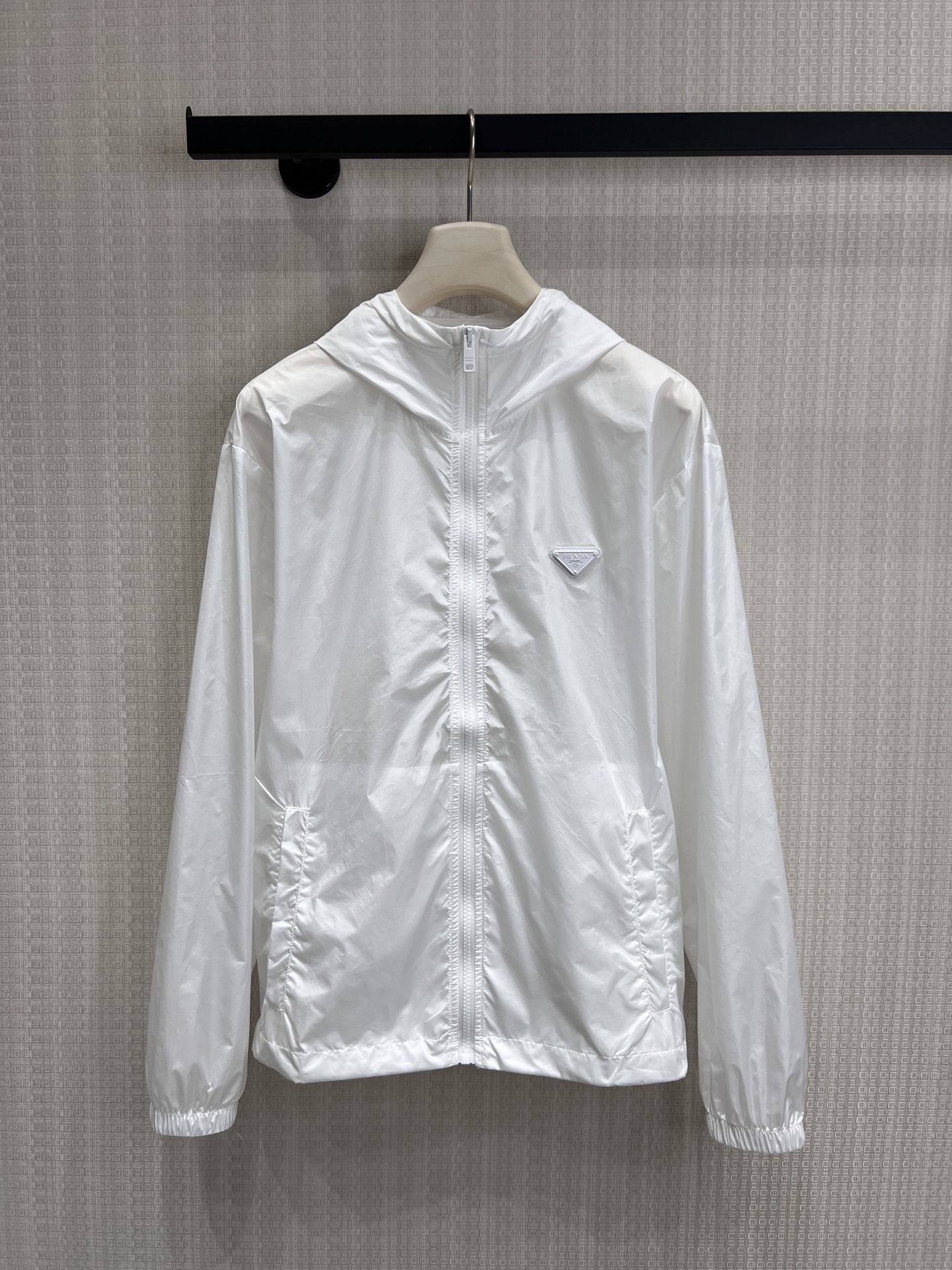 NO:863335,Pra** classic triangle logo hooded sun protection jacket. The pure white tone has a refreshing and high-end feel. The iconic triangle logo low-key highlights the brand style. Lightweight and breathable windproof fabric, with both sun protection and practical functions, no burden for summer travel. Loose hooded version, neat tailoring does not flatter the figure, easy to create casual and high-end street wear. Ready for sale smL, prada, hats,19860909Pra**经典三角标连帽防晒衣 纯净白调自带清爽高级感,标志性三角徽标低调彰显品牌格调 轻薄透气的防风面料,兼具防晒与实用功能,夏日出行无负担 宽松连帽版型,利落剪裁不挑身材,轻松打造随性高级的街头穿搭现货出售smL,,prada,hats,,Women's clothing
