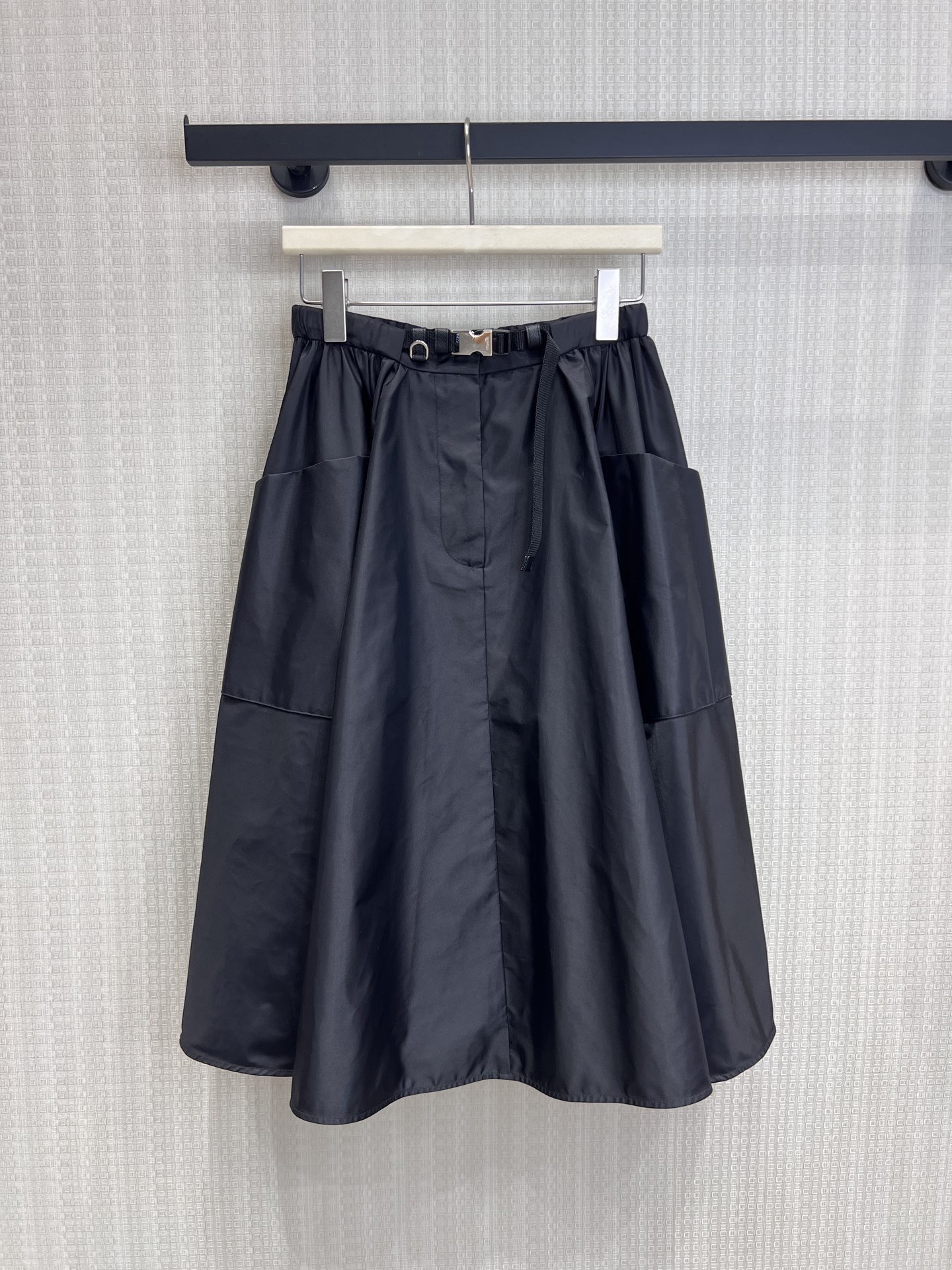 NO:863268,26 spring and summer new product Pra**'s iconic regenerated nylon fabric has a matte high-end texture, is stiff and anti-wrinkle, and is draped and stylish. The soft pleats create a three-dimensional umbrella shape, with functional belt and metal buckle details. It combines elegant feminine lines with practical workwear attributes. The large pockets on both sides are designed to take into account both style and practicality. The mid-length A-line version perfectly modifies the waist and hip lines, hides the flesh and makes you look slimmer, and is suitable for many styles. Ready for sale smL, prada,1986090926春夏新品 Pra**标志性再生尼龙面料,自带哑光高级质感,挺括抗皱,垂坠有型. 柔和褶皱打造立体伞状廓形,搭配机能风腰带与金属扣细节, 兼具优雅女性化线条与实用工装属性,两侧大口袋设计兼顾造型与实用性, 中长A字版型完美修饰腰臀线条,藏肉显瘦,适配多风格搭配.现货出售smL,,prada,,Women's clothing