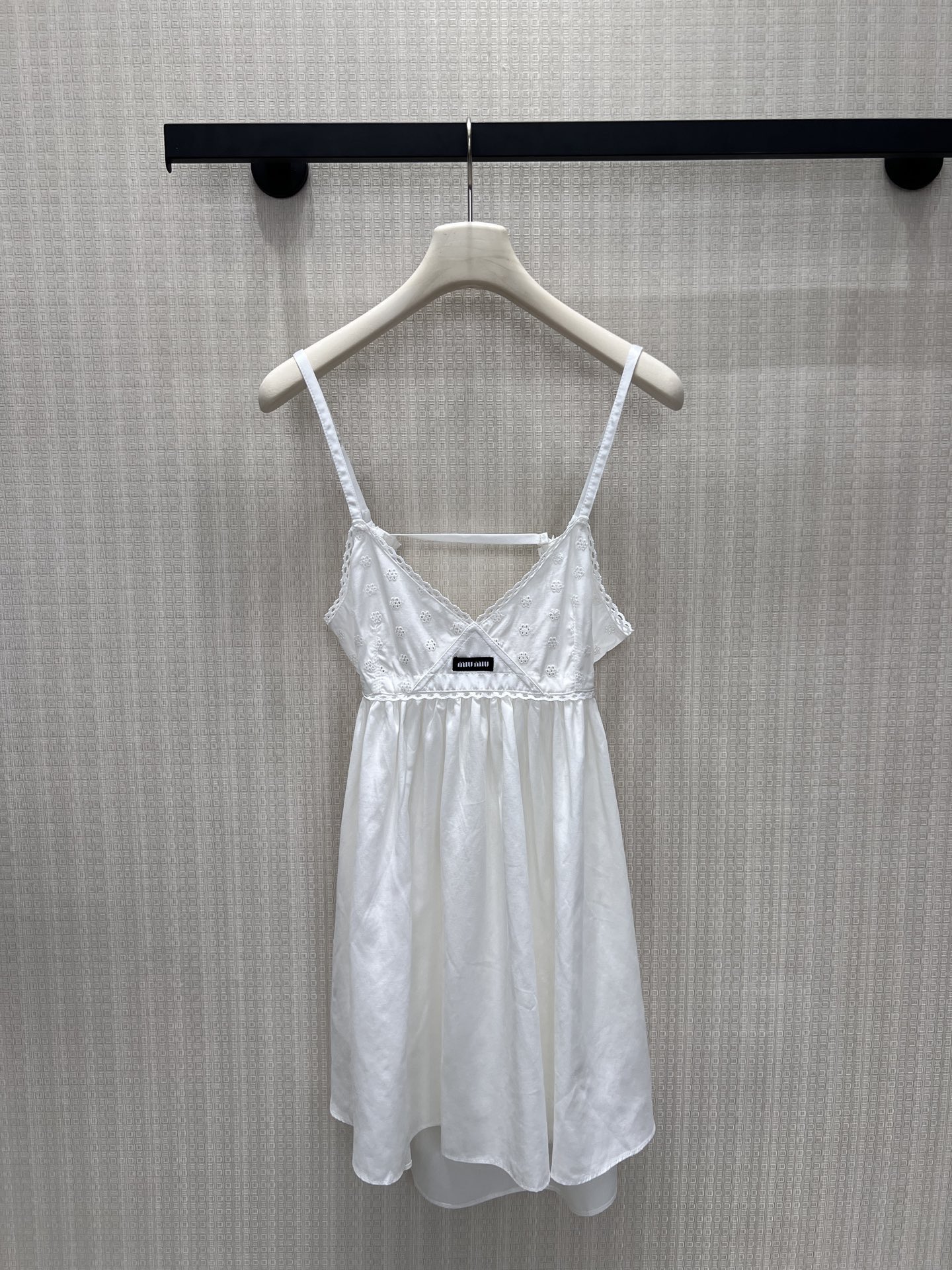 NO:867174,26 spring and summer new product Miu** style hollow embroidered suspender dress outlines the romance of girls with pure white tones. The V-neck is matched with lace, which gently modifies the neck line; the waist is cut with an umbrella hem, which hides the body and makes it look slimmer and has a smart and fairy air. The full-frame embroidery texture is delicate, and the brand woven label is a low-key finishing touch. It is suitable for wearing alone or as an inner layer, easily unlocking the exquisite and high-end sense of the retro college style. Ready for sale smL,, miumiu, skirts,1986090926春夏新品 Miu**风镂空刺绣吊带连衣裙 以纯净白调勾勒少女浪漫.V领搭配蕾丝花边,温柔修饰颈部线条；收腰伞摆剪裁,藏肉显瘦又自带灵动仙气.全幅刺绣肌理细腻,品牌织标低调点睛,单穿或内搭都适配,轻松解锁复古学院风的精致高级感.现货出售smL,,miumiu,skirts,,Women's clothing