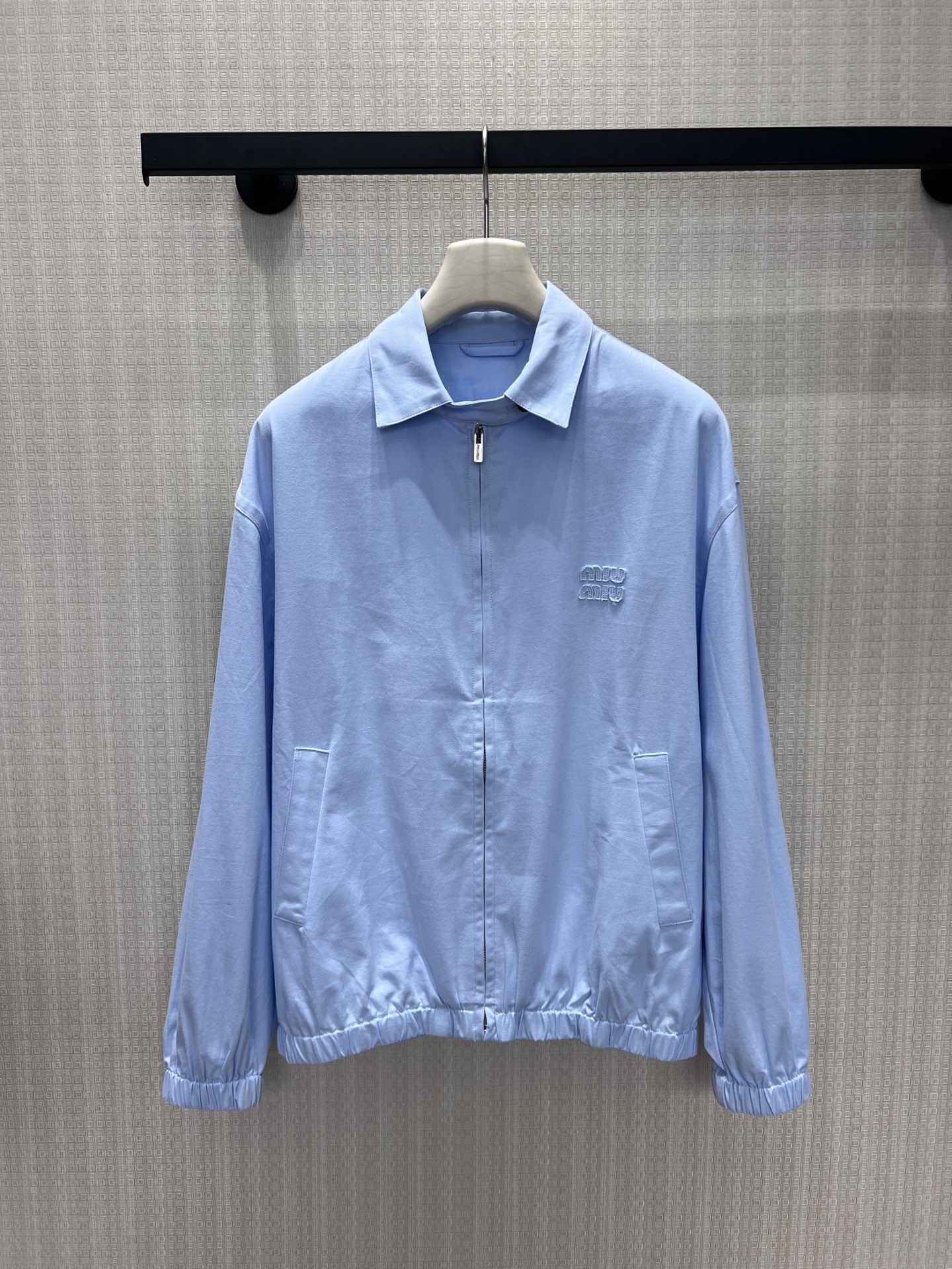NO:867337,New product for spring and summer 26, light blue MIU** jacket, with minimalist tailoring to interpret a relaxed and high-end feel. The soft sky blue comes with a cooling filter, the lapel + zipper design is neat and elegant, and the logo embossed on the chest is low-key and noble. The loose silhouette and gathered hem balance neatness and casualness, and the fabric is drapey and breathable. It is an effortless dressing in spring, and it is easy to achieve the cool rich family atmosphere. Ready for sale smL,, miumiu, jackets &  coats,jackets & coats,1986090926春夏新品 浅蓝调MIU**夹克外套 ,以极简剪裁诠释松弛高级感.柔和的天空蓝自带清冷滤镜,翻领+拉链设计利落大气,胸前压印logo低调显贵.宽松廓形与收束下摆平衡利落与随性,面料垂坠透气,是春日里不费力的穿搭王牌,轻松拿捏清冷富家千金氛围.现货出售smL,,miumiu,jackets & coats,jackets & coats,,Women's clothing