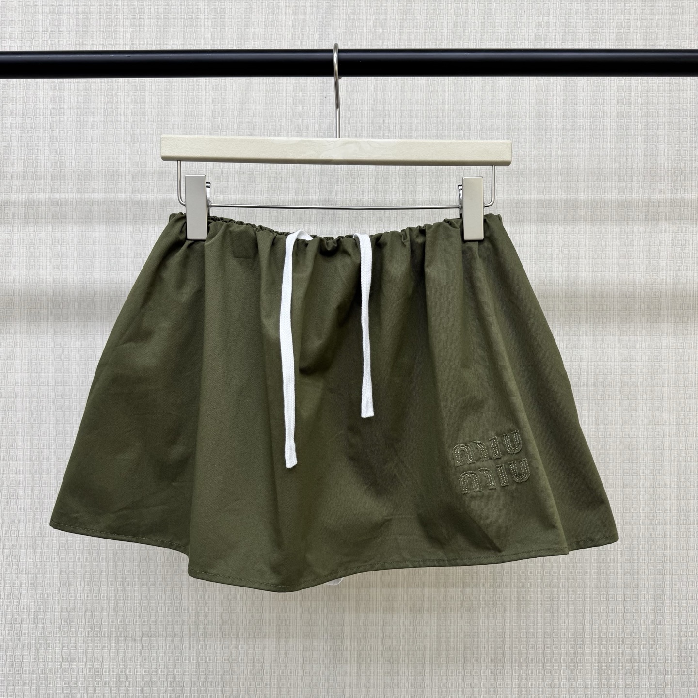 NO:891604,MiuM** 2026 spring and summer series olive green flower bud short skirt, cotton fabric is light and comfortable, A-line version + elastic waist design, with safety pants inside, super convenient to wear!  The embroidered logo on the skirt is perfect for details. The flower bud hem is playful and makes the legs look longer. It is easy to achieve sweet and cool college style. It is very suitable for daily outings, afternoon tea, and citywalk. Paired with sweaters or shirts, it will directly add youthful vitality. Ready for sale SML,, miumiu, skirts, shirts,19860909MiuM**2026春夏系列橄榄绿花苞短裙,棉质面料轻盈舒适,A字版型+松紧腰设计,内有安全裤穿着超方便！裙身刺绣Logo,细节满分,花苞裙摆俏皮又显腿长,甜酷学院风轻松拿捏～日常出街、下午茶、citywalk都很适合,搭配针织衫或衬衫,青春活力感直接拉满 现货发售SML,,miumiu,skirts,shirts,,Women's clothing