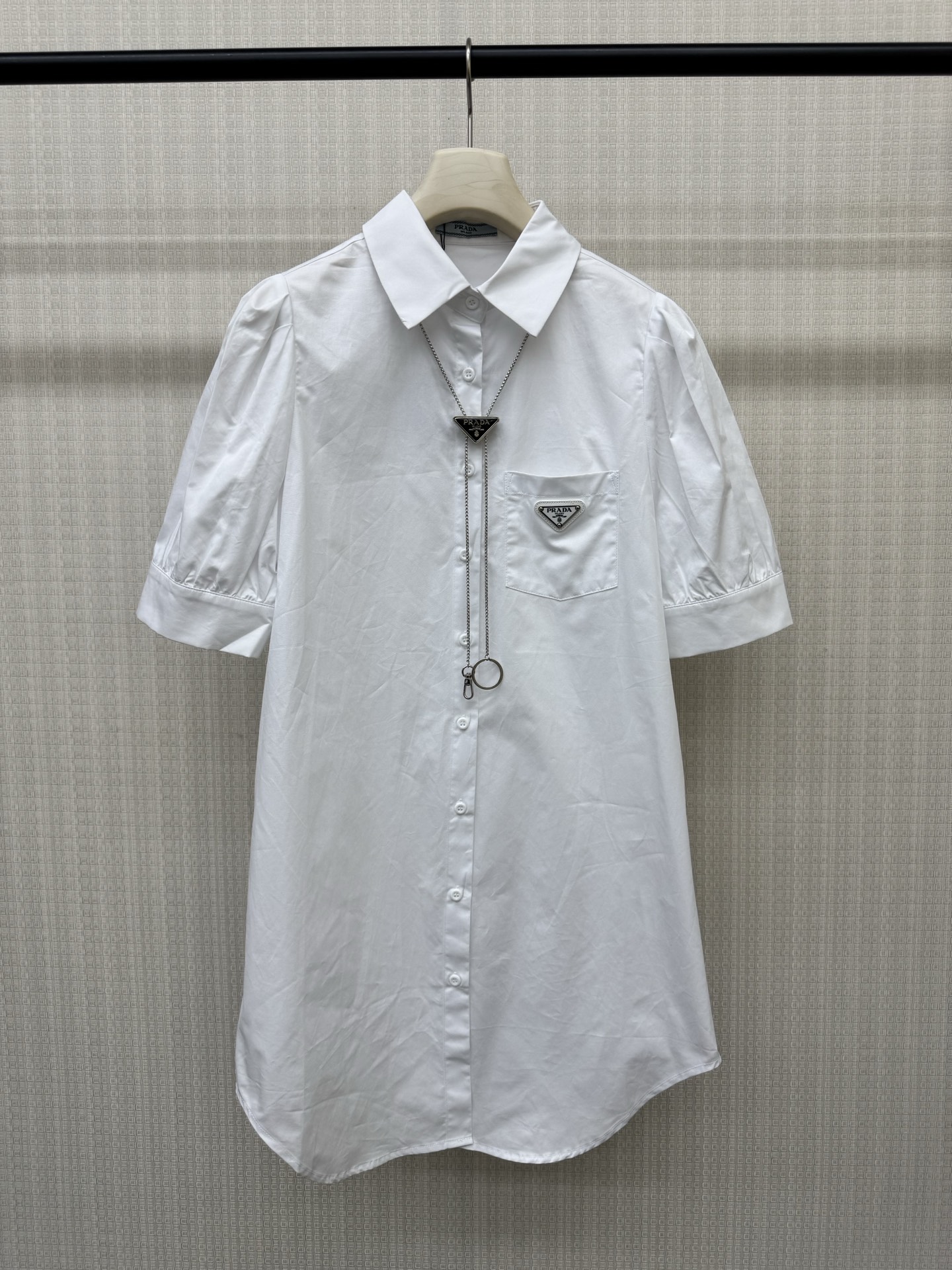 NO:893879,Pra**26 summer new triangle chain shirt dress, made of high-count washed cotton, dry, crisp and breathable, super comfortable to wear!  Lapel + full button placket + hardware triangle necklace. Five-point puff sleeves modify the arm lines, and the triangle metal logo on the left chest is very recognizable. The straight and loose mid-length version covers the hips and makes you slimmer. It is not picky about your figure. It looks great when worn alone or with accessories. It can be easily used for commuting, shopping, and traveling. It is practical and fashionable!  Black and white ready for sale sML real shot details, prada, skirts, shirts, necklace,19860909Pra**26夏季新款三角标链条衬衫连衣裙,高支水洗棉材质,干爽挺括又透气,穿着超舒适！翻领+全开纽扣门襟+配五金三角标项链 五分泡泡袖修饰手臂线条,左胸三角金属标超有辨识度.直筒宽松中长版型,遮胯显瘦,不挑身材,单穿或搭配配饰都很出彩,通勤、逛街、出游都能轻松驾驭,实用又时髦！黑色白色 现货发售sML实拍细节图,,prada,skirts,shirts,necklace,,Women's clothing