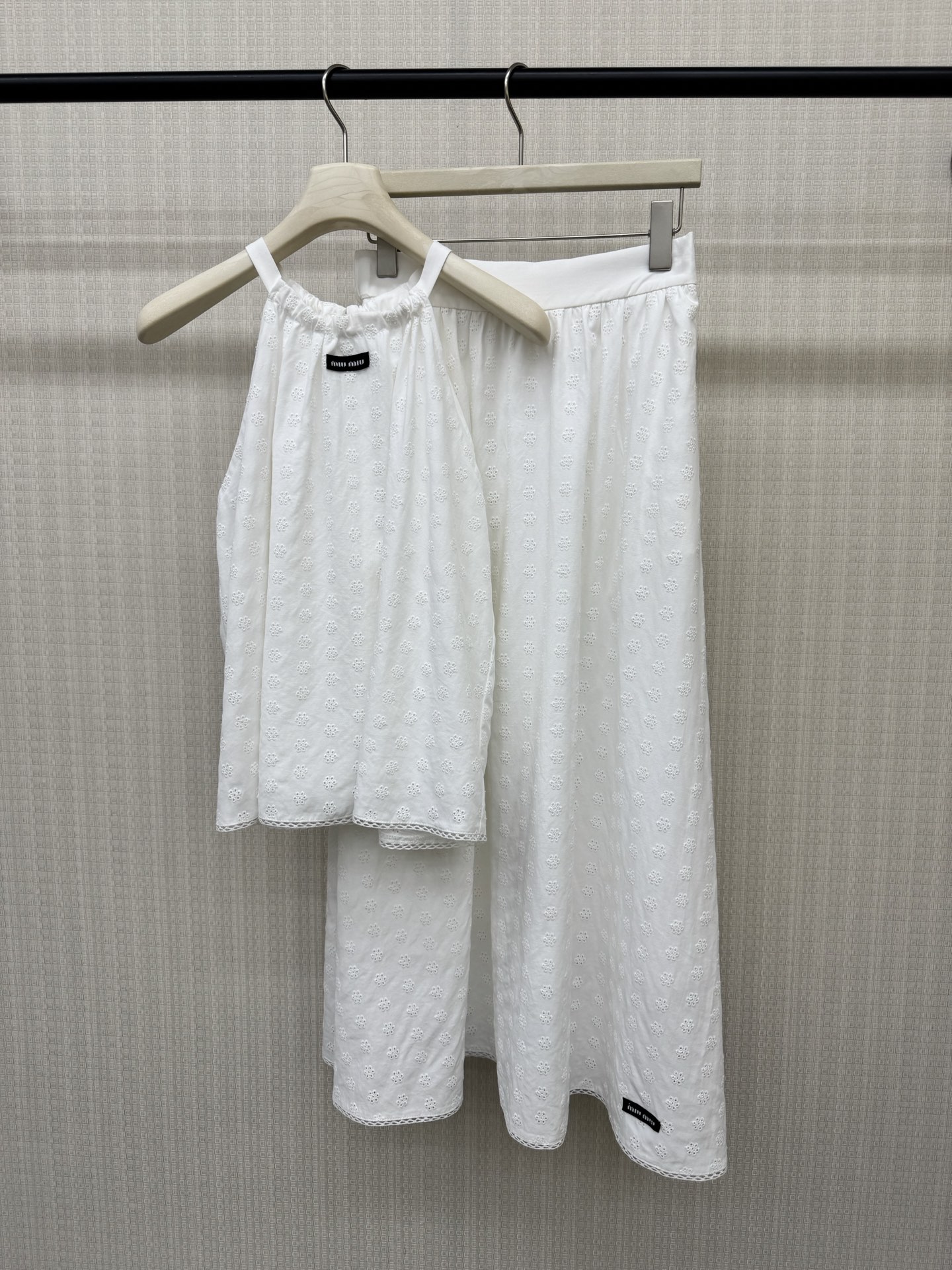 NO:901328,26 spring and summer new products Miu** style hollow embroidered camisole + mid-length elastic waist skirt suit + wooden platycodon vine woven belt  The fabric uses pure white tones to outline the romance of girls. The micro-label badge is matched with lace, which gently modifies the neck line; the waist is cut with an umbrella hem, and the mid-length skirt hides the body to look slimmer and has a smart and fairy spirit. The full-frame embroidery texture is delicate, and the brand woven label is a low-key finishing touch. It is suitable for wearing alone or as an inner layer, easily unlocking the exquisite and high-end sense of retro style. Ready for sale sml real shot details,, miumiu, skirts,1986090926春夏新品 Miu**风镂空刺绣吊带背心+中长款松紧腰半身裙套装+木质桔梗藤蔓编织腰带 面料以纯净白调勾勒少女浪漫.微标胸章搭配蕾丝花边,温柔修饰颈部线条；收腰伞摆剪裁,中长款半身裙藏肉显瘦又自带灵动仙气.全幅刺绣肌理细腻,品牌织标低调点睛,单穿或内搭都适配,轻松解锁复古风的精致高级感.现货出售smL 实拍细节图,,miumiu,skirts,,Women's clothing