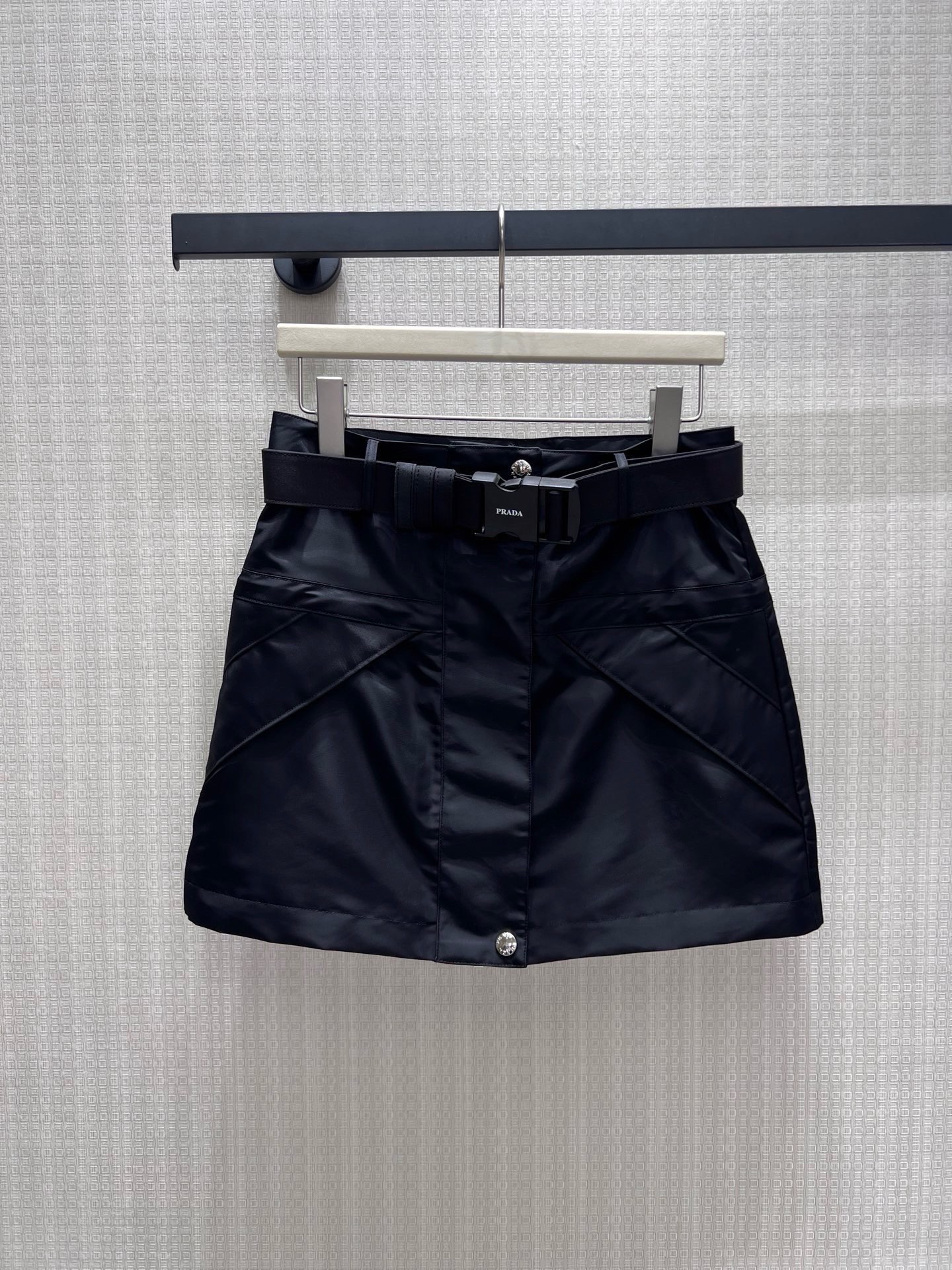 NO:952429,26 spring and summer new skirt Pra** Iconic regenerated nylon skirt reshapes workwear aesthetics with neat tailoring. The matte fabric has a cool feel, the belt buckle and triangle logo point out the identity, and the front snap buttons and draping lines hide the ingenuity. The high-waisted A-line version has optimized proportions, and the neat lines bring a sassy aura. It perfectly balances street function and light luxury texture. It is a wardrobe essential to create an effortless sense of luxury. Ready in stock sml  Actual detailed pictures,,prada,skirts,1986090926春夏新品半裙 Pra** 标志性再生尼龙半裙,以利落剪裁重塑工装美学.哑光面料自带酷感,腰带扣与三角徽标点明身份,前襟按扣与立体裁线暗藏巧思.高腰A字版型优化比例,利落线条自带飒爽气场,将街头机能与轻奢质感完美平衡,是打造不费力高级感的衣橱必备单品.现货sml 实拍细节图,,prada,skirts,,Women's clothing