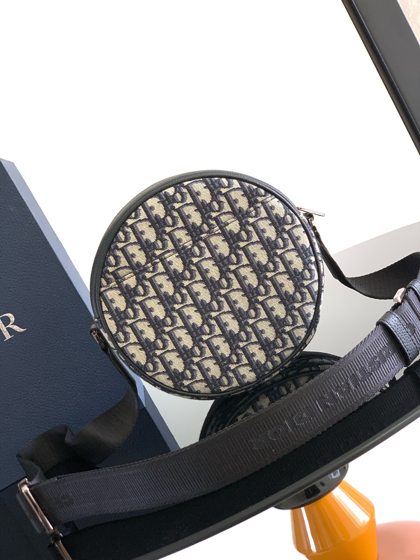 这款 Dior Yoyo 拉链信使包时尚实用。圆形款式,采用米色和黑色 Oblique 印花面料等材质
