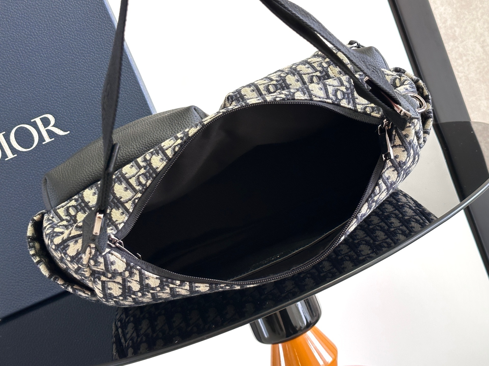 这款 Rider Soft 水饺包是二零二五秋季男装系列新品,兼具实用功能与时尚设计。采用米色和黑色 O