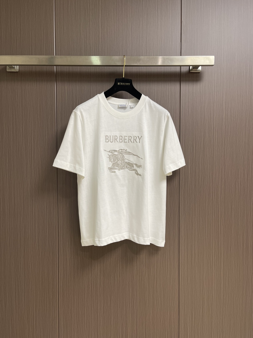 NO:598772,Burberry  Thin-thread war horse embroidery round-neck short-sleeved T-shirt is made of high-quality pure cotton fabric, which is skin-friendly and breathable. The black and off-white tones are classic and versatile. The brand knight logo on the front adopts precision embroidery technology. The silk thread is full in color, the stitching is delicate and three-dimensional, and the pattern is rich in layers, highlighting the brand's high recognition. The round-neck structure is processed by overlocking technology, and the collar fits the neck and is not easy to deform. The body is sewn using industrial-grade flat stitching technology, and the stitches are smooth.  It is uniform, and the stitch length at the hem and cuffs is fine and firm. From the selection of pure cotton fabrics to the control of embroidery details, every process reflects Burberry's pursuit of craft precision and classic style. It not only retains the daily practicality of the T-shirt, but also shows the brand's light luxury recognition through exquisite embroidery. It is a fusion of casual style and exquisite craftsmanship. The overall line routing is straight and delicate, the fabric is comfortable and soft, and the color is consistent without color difference.  It can be matched with the same style to create a fashionable look, and can be used in various occasions. Customized accessories, complete with three standards, same style for men and women!  Size XS-L,,burberry,T-shirt,tees,t-shirt,alexander wang19860909Burberry 细线战马刺绣圆领短袖T恤,选用高品质纯棉面料,触感亲肤透气,黑色与米白色调经典百搭.正面品牌骑士标识采用精密刺绣工艺,丝线色泽饱满、针脚细腻立体,图案层次丰富,彰显品牌高辨识度.圆领结构经锁边工艺处理,领口贴合颈部且不易变形.衣身车缝采用工业级平缝工艺,线迹平整均匀,下摆与袖口处针距细密牢固.从纯棉面料的甄选到刺绣细节的把控,每一道工序都体现Burberry对工艺精度与经典风格的追求,既保留T恤的日常实穿性,又通过精致刺绣展现品牌的轻奢辨识度,是休闲风格与精湛工艺的融合之作.整体走线平直细腻,面料舒适柔软,颜色一致无色差 能与同款搭配营造时尚造型,驾驭各种场合,定制辅料,三标齐全,男女同款！尺码XS-L,,burberry,T-shirt,tees，t-shirt,alexander wang,Men's clothing