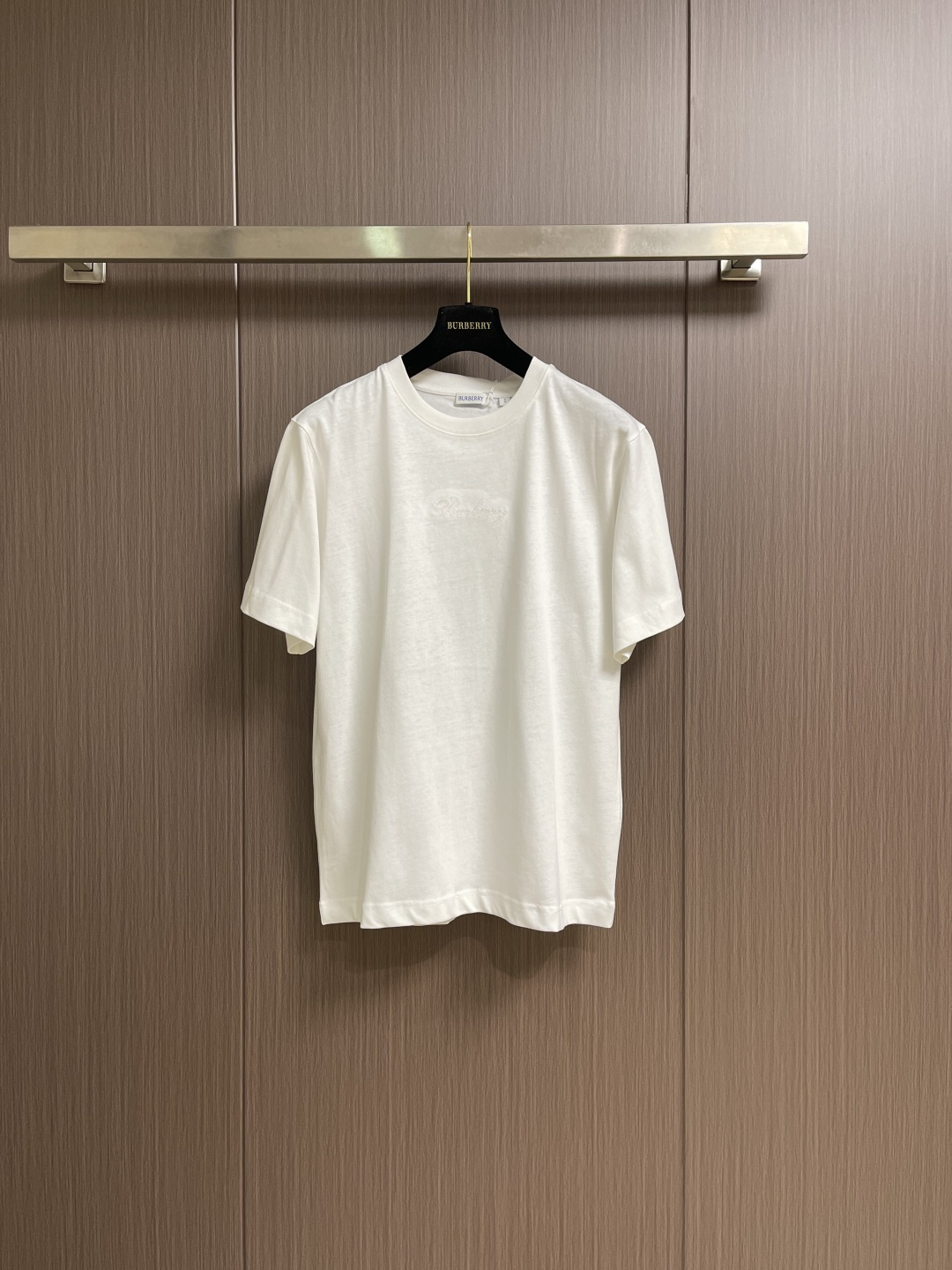 NO:597881,Burberry plaid back letter embroidered round neck short-sleeved T-shirt, made of 15S fine cotton plain weave, white 230g, black 310g; matching  32S double yarn tensioner thread, 300g. Made of pure cotton plain weave fabric, this weave has a tight structure, giving the fabric a crisp texture and excellent durability, while retaining the natural breathability and skin-friendly properties of cotton. The plain weave fabric is not easy to deform and avoid  It avoids an overly baggy casual feel and provides a neater silhouette. The chest and back are embellished with letter logo embroidery, forming a visual rhythm that echoes the front and rear, all presented through chain stitch embroidery technology. These logos are also embroidered with high precision  Craftsmanship ensures clear edges, firmness and durability. The unique embroidery technique, whose stitches are interlocking like a chain, has a stronger three-dimensional sense, softer touch, and a unique texture and luster. Using this process to present the classic plaid pattern is an innovative deconstruction of the brand's traditional elements. It transforms the original flat pattern into a three-dimensional texture with handicraft warmth, which greatly enhances the sophistication and value of the design. The overall wiring is straight and delicate, the fabric is comfortable and soft, and the colors are consistent and without color difference.  It can be matched with the same style to create a fashionable look, and can be used in various occasions. Customized accessories, complete with three standards, same style for men and women!  Size XS-L,,burberry,T-shirt,tees,t-shirt,alexander wang19860909Burberry 格子背字母刺绣圆领短袖T恤,采用15S精棉平纹,白230g、黑310g；搭配 32S双纱拉架螺纹,300g.采用纯棉平织面料,这种织法结构紧密,赋予面料挺括的骨感和优异的耐久性,同时保留了棉天然的透气与亲肤特性.平织面料不易变形,避免了过于松垮的随意感,提供了更为利落的轮廓.前胸及背部均点缀字母徽标刺绣,构成了前后呼应的视觉节奏,均通过链式缝线刺绣工艺呈现.这些徽标同样采用高精度的刺绣工艺,确保边缘清晰、牢固耐用.独特的刺绣技法,其线迹如同链条般环环相扣,立体感更强、触感更柔软,且具有独特的纹理光泽.将经典的格纹图案用此种工艺呈现,是对品牌传统元素的一次创新解构,它将原本平面的图案转化为具有手工艺温度的立体肌理,极大地提升了设计的精致度和价值感.整体走线平直细腻,面料舒适柔软,颜色一致无色差 能与同款搭配营造时尚造型,驾驭各种场合,定制辅料,三标齐全,男女同款！尺码XS-L,,burberry,T-shirt,tees，t-shirt,alexander wang,Men's clothing