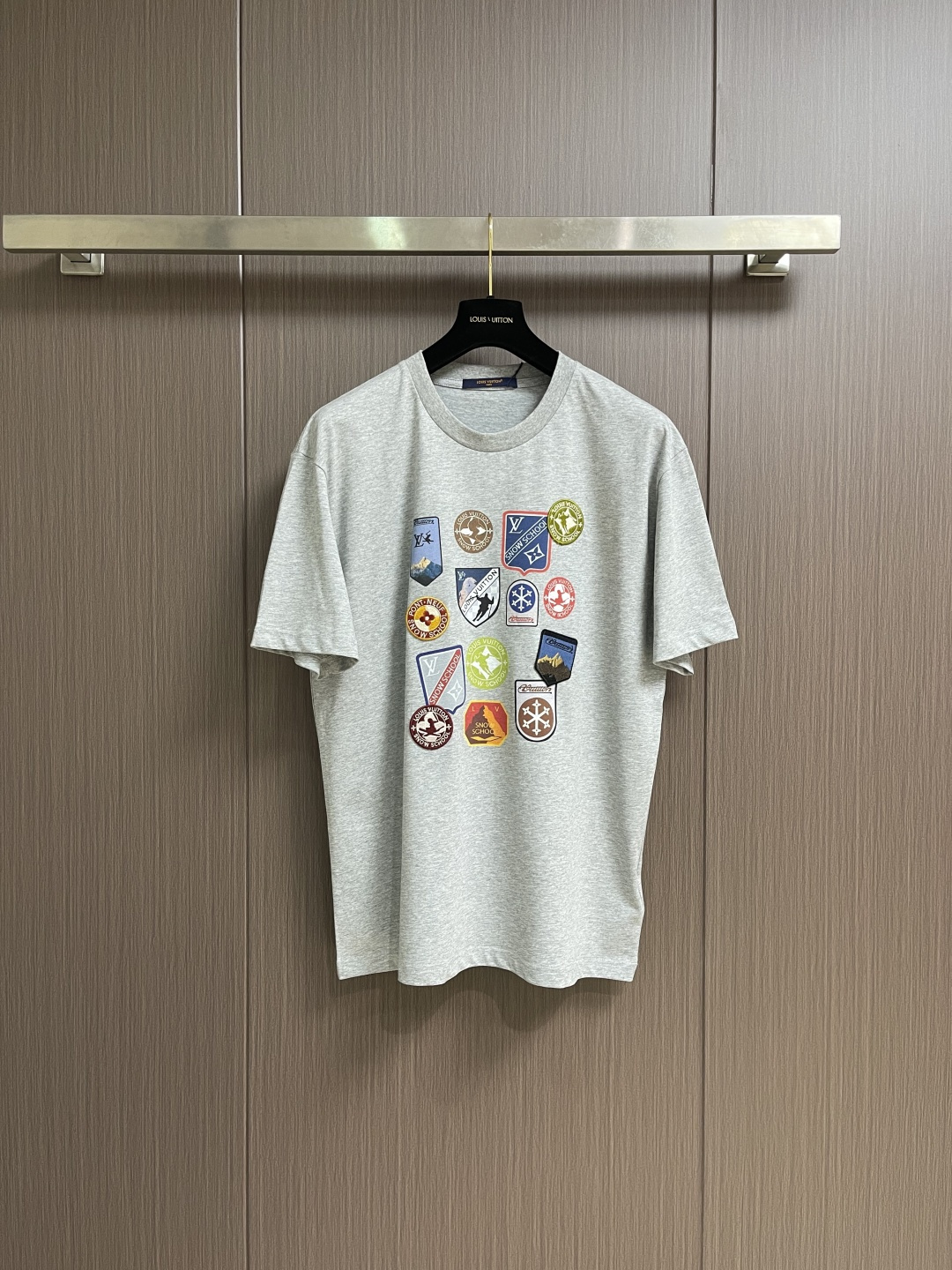 NO:597877,LV  SKI Ski Sleeve Round Neck Short Sleeve T-shirt. The T-shirt is made of pure cotton fabric, which is skin-friendly, breathable and has a good drape. The neckline is designed with a round neck and is processed by double-needle seaming process. The collar shape is flat and not easy to deform. The chest badge is combined with hand embroidery + patching technology. Multiple badges with different patterns are precisely sewn in position. The embroidery stitches are fine, the edge of the patch is flat, the colors are rich and the layers are distinct, creating a perfect look.  Decorative effect with visual impact. The overall cut is a loose-shouldered version, and the multi-piece structure is spliced to ensure comfort and freedom when wearing. The fabric is dyed with an environmentally friendly process, and the gray color is uniform and has excellent color fastness. It is a personalized item that combines exquisite embroidery technology with a casual T-shirt style. It has both fashion sense and wearing comfort. The overall wiring is straight and delicate, the fabric is comfortable and soft, and the color is consistent without color difference.  It can be matched with the same style to create a fashionable look, and can be used in various occasions. Customized accessories, complete with three standards, same style for men and women!  Size S-XL,,louis vuitton,T-shirt,tees,t-shirt,alexander wang19860909LV SKI滑雪系袖圆领短袖T恤,该T恤采用全棉面料,亲肤透气且具良好垂坠感.领口为圆领设计,经双针锁边工艺处理,领型平整不易变形.胸前徽章运用手工刺绣＋贴布工艺结合,多枚不同图案的徽章经精准对位缝制,刺绣针脚细密、贴布边缘平整,色彩丰富且层次分明,打造出极具视觉冲击力的装饰效果.整体剪裁为宽松落肩版型,多片式结构拼接确保穿着时的舒适自由度.面料经环保染色工艺,灰色色泽均匀且色牢度优异,是一件将精湛刺绣工艺与休闲T恤风格融合的个性单品,兼具时尚感与穿着舒适度.整体走线平直细腻,面料舒适柔软,颜色一致无色差 能与同款搭配营造时尚造型,驾驭各种场合,定制辅料,三标齐全,男女同款！尺码S-XL,,louis vuitton,T-shirt,tees，t-shirt,alexander wang,Men's clothing