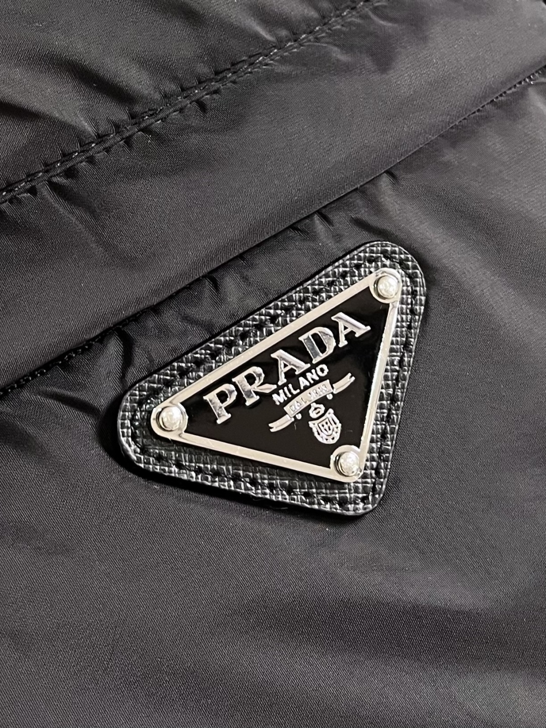 PRADA 2025FW秋冬新款连帽羽绒外套，选用品牌标志性的再生尼龙面料，与传统尼龙性能相当，具备高强